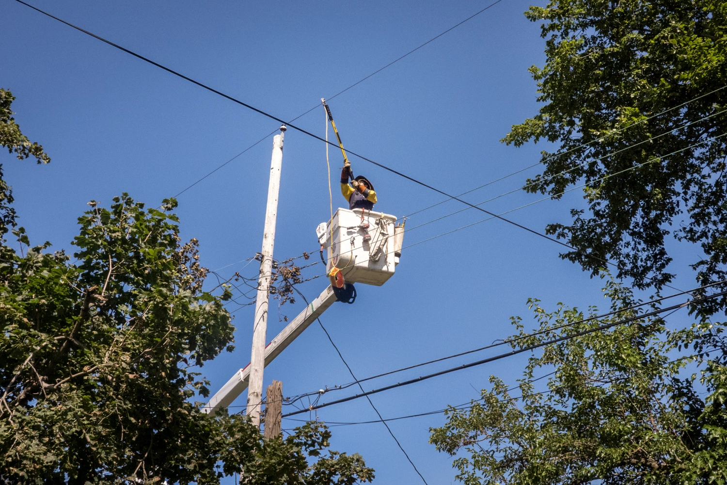 Workers repair an electrical line damaged during a recent storm on August 20, 2026 in Gary, Ind.