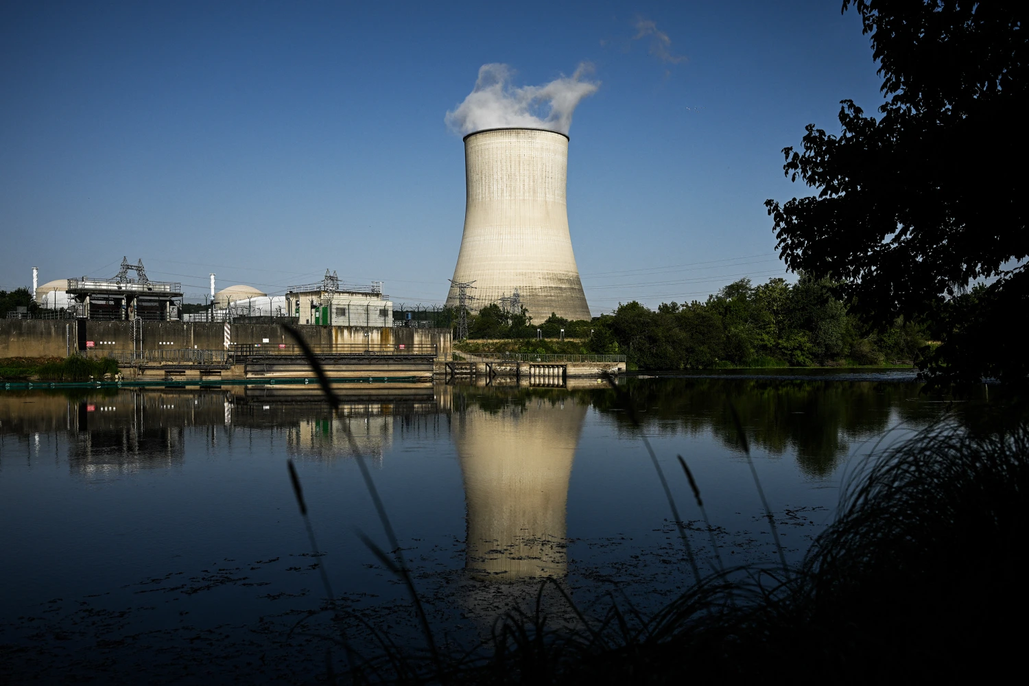 One of the two cooling towers of the Civaux nuclear power plant is reflected in the Vienne river in Civaux, south-western France, on June 24, 2026. 