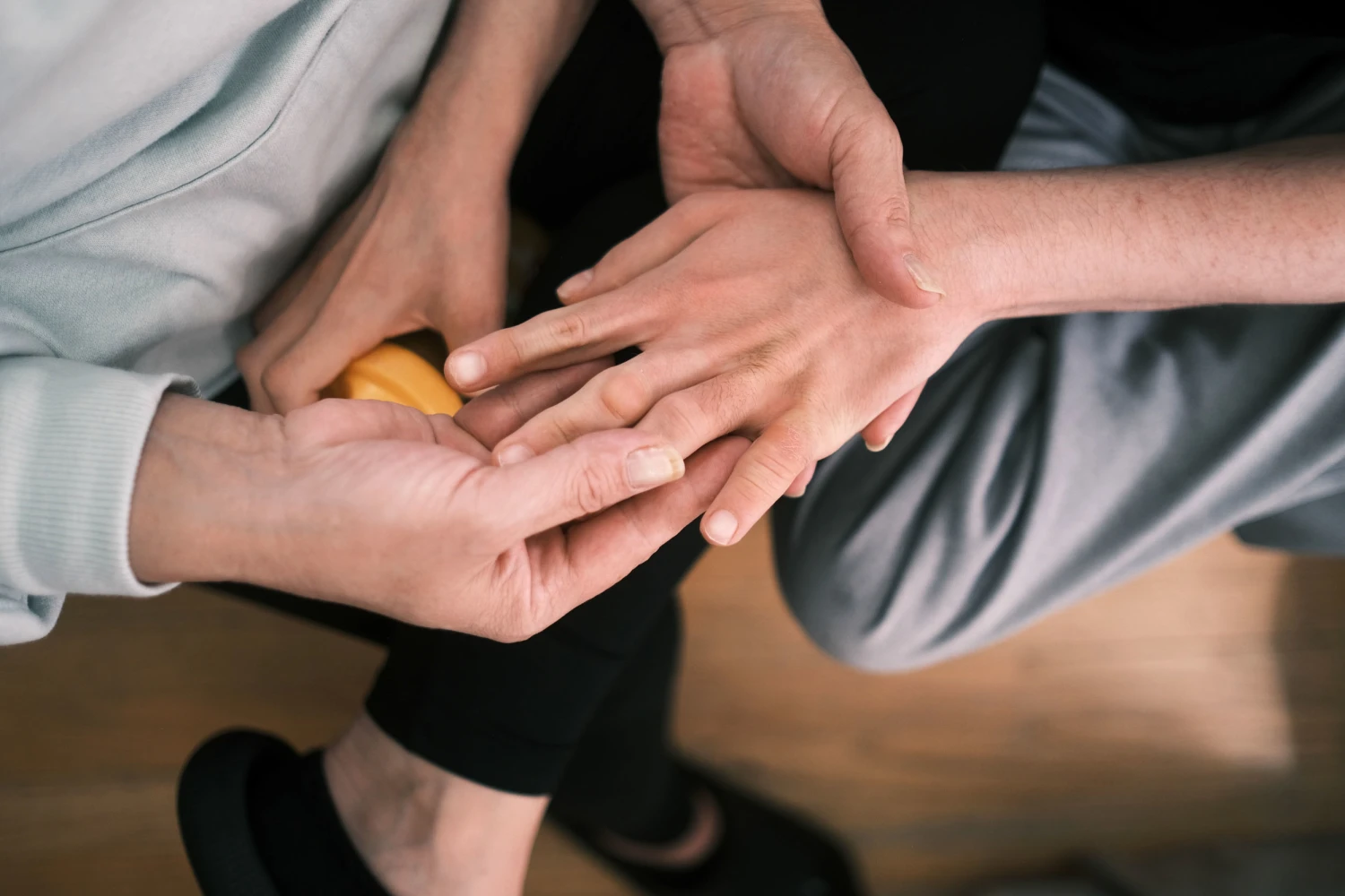 Melissa Gonce holds her 28-year-old son Jason's hand at their home near Baltimore on May 4, 2026. Jason has a rare chromosome disorder that requires daily care.