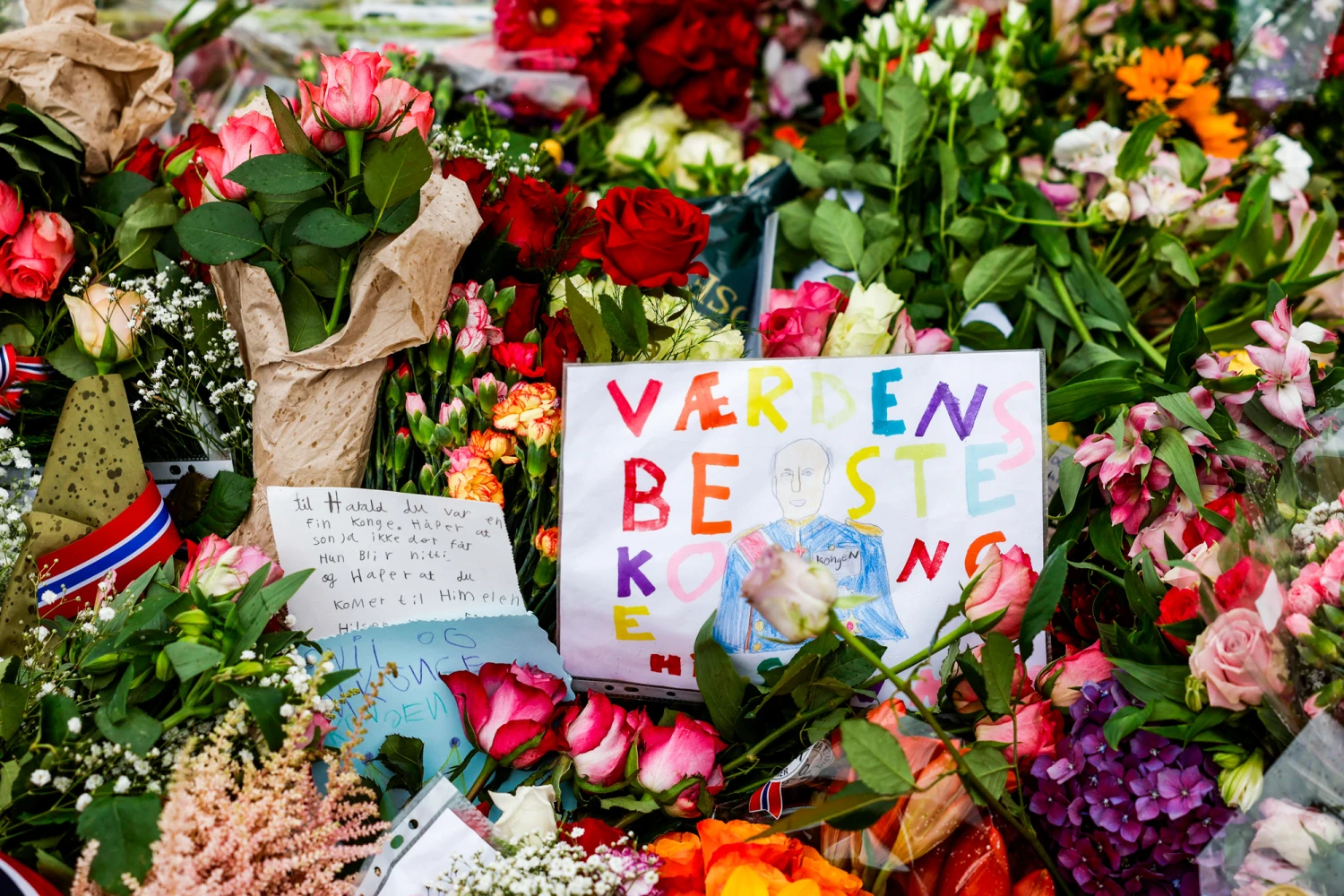 Flowers and children's drawings lay outside the Royal Palace square as mourners gather to pay tribute to King Harald V of Norway who passed away, in Oslo on Aug. 29, 2026.