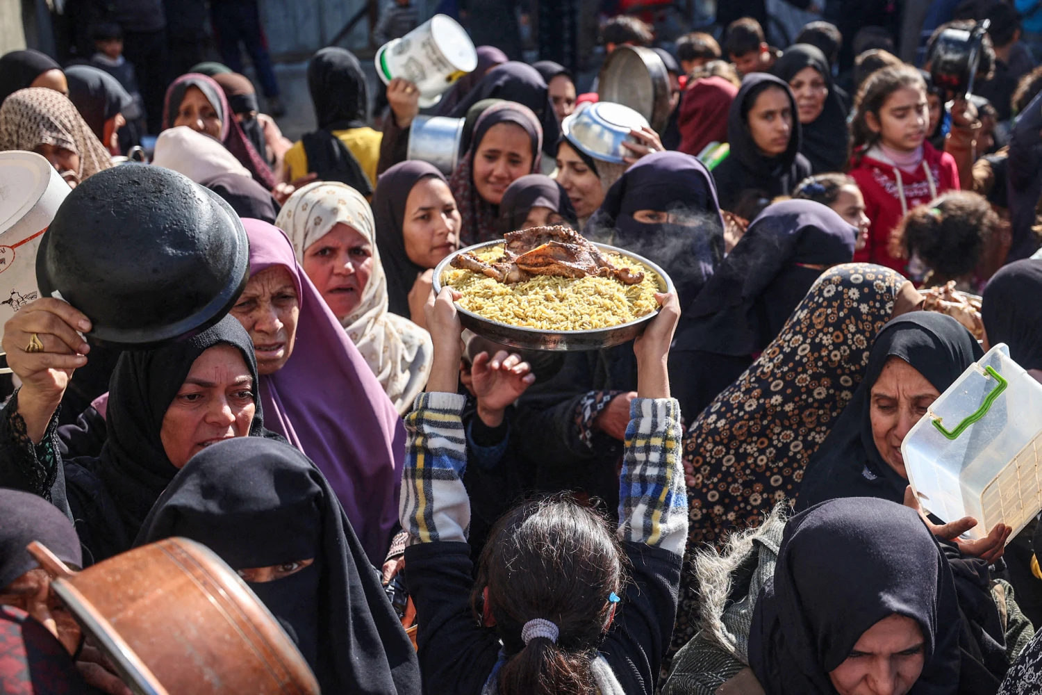 Displaced Palestinians gather to receive food portions at a charity kitchen in the Nuseirat refugee camp in the central Gaza Strip on Dec. 20, 2025.