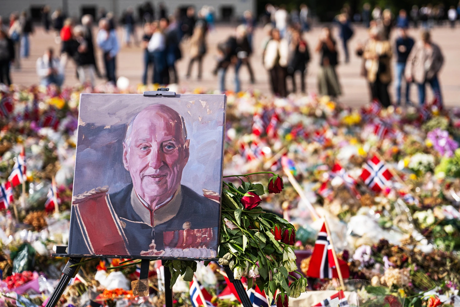 A painted portrait of Norway's King Harald V is displayed among flowers and Norwegian flags at a makeshift memorial outside the Royal Palace in Oslo, Norway, on September 8, 2026, on the eve of the late monarch's state funeral.