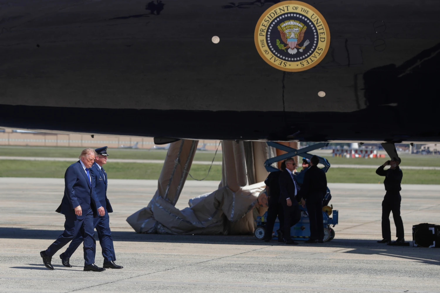 President Donald Trump, left, is escorted by Air Force Col. Christopher M. Robinson, commander of the 89th Airlift Wing, as he walks from Marine One before boarding Air Force One, as U.S. Air Force personnel work after an emergency inflatable slide deployed on Air Force One before Trump arrived to board at Joint Base Andrews, Md., Wednesday, Sept. 9, 2026.