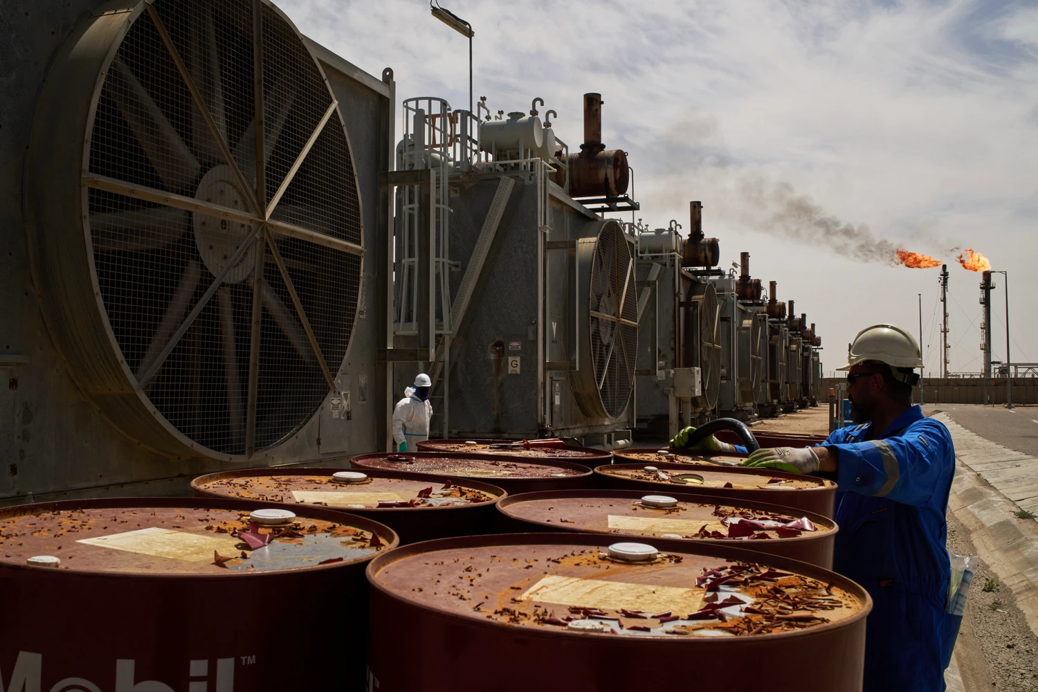 A worker collects engine oil as he works at a degassing station at Zubair oil field near Basra, Iraq, March 28, 2026.