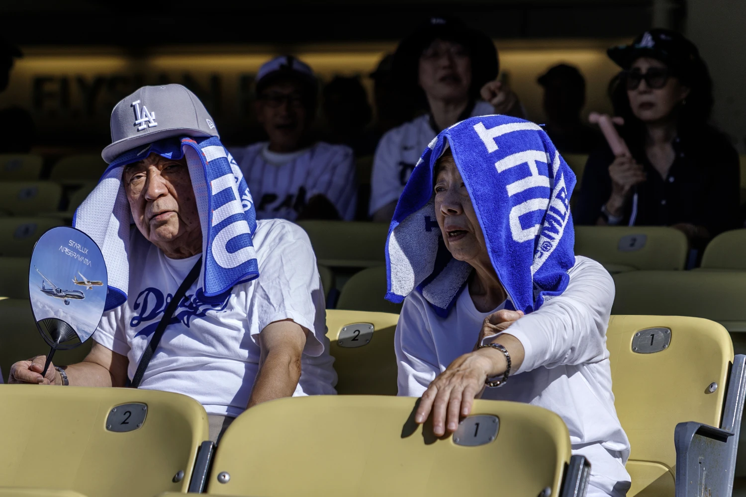 Dodger fans  Haruya Shibata, left, and Yoshiko Shibata, visiting from Japan, wear towels on their heads for shade during he Southern California heat wave before the game against the Boston Red Sox at Dodger Stadium on August 1, 2026 in Los Angeles, CA.