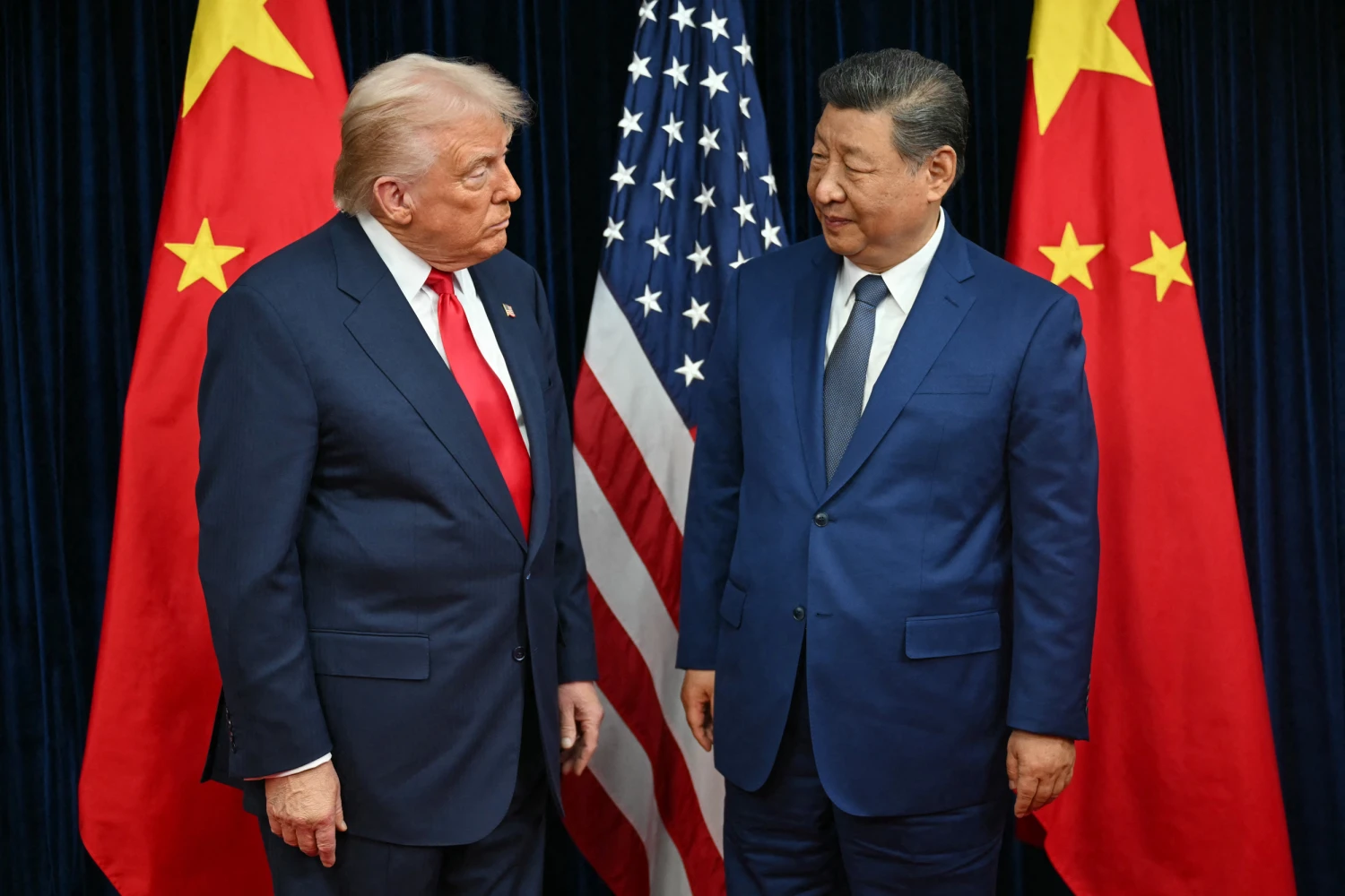 U.S. President Donald Trump (L) and China's President Xi Jinping greet each other as they arrive for talks at the Gimhae Air Base, located next to the Gimhae International Airport in Busan on October 30, 2025.
