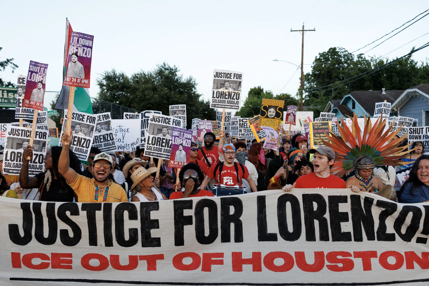 People hold signs while marching through the Magnolia Park neighborhood during a rally to protest the killing of Lorenzo Salgado Araujo in Houston, Texas on July 24, 2026.