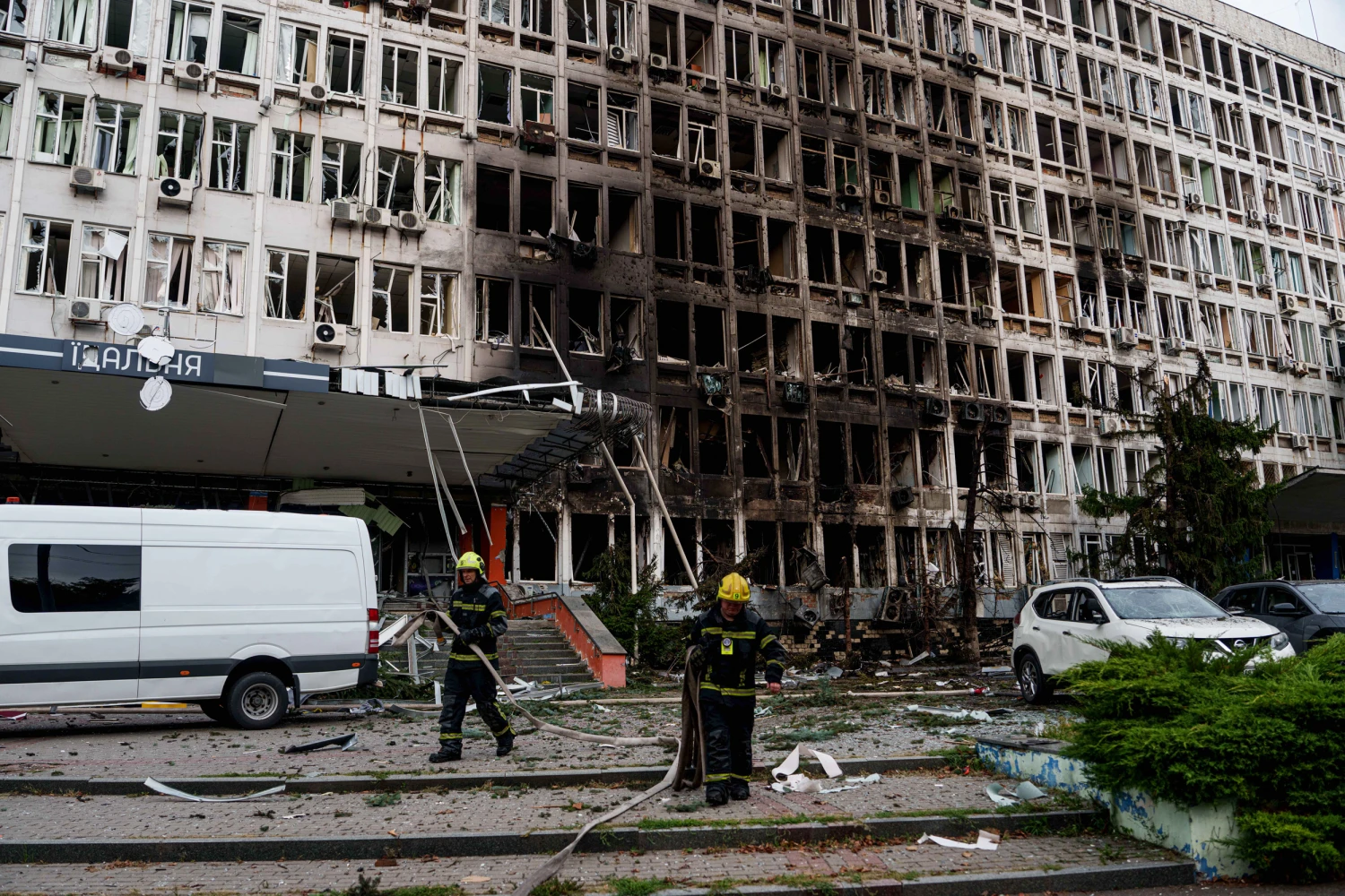 Rescuers gather fire hoses in front of an office building damaged by a Russian drone strike in Kyiv, Ukraine, Wednesday, Sept. 23, 2026.
