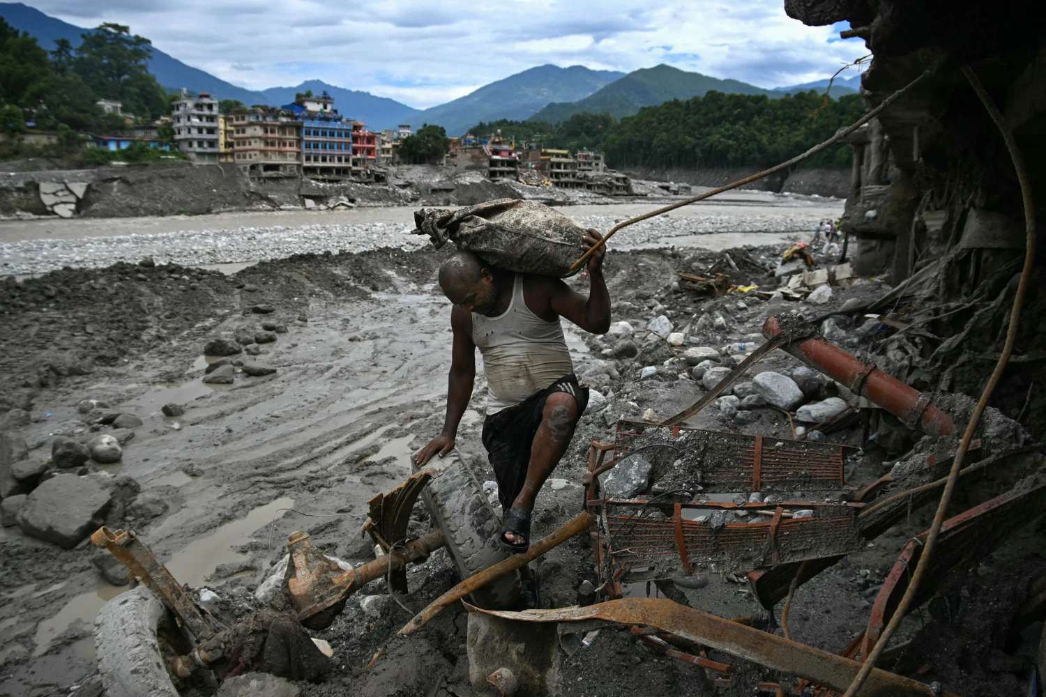 A man carrying his belongings walks past a damaged house in the aftermath of flash floods at Trishuli in Nepal's Nuwakot district on Sept., 11, 2026.