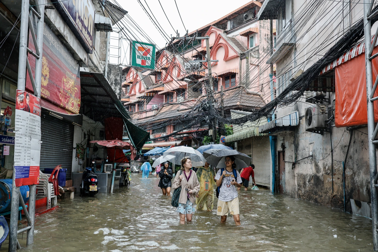 People wade through floodwaters in the Bang Bua district of Bangkok on September 26