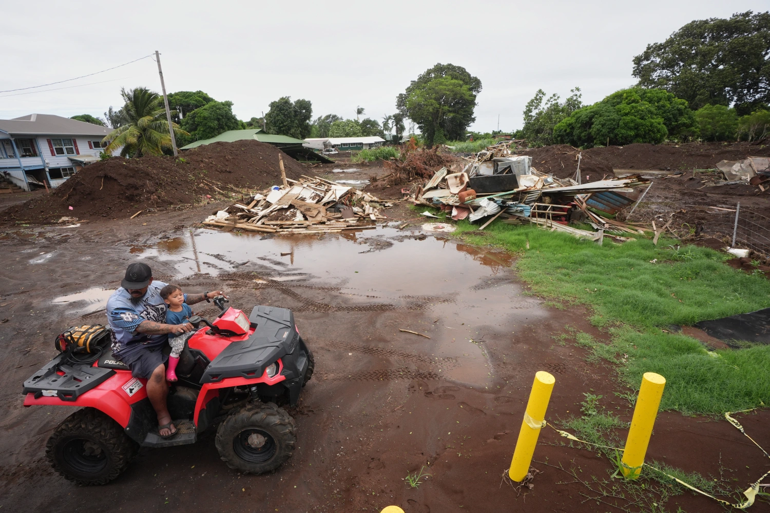 A man rides with his son near where a home was destroyed during last month's Hurricane Lala, as floodwaters from Hurricane Nolo recedes Sunday, Sept. 27, 2026, in Naalehu, Hawaii.