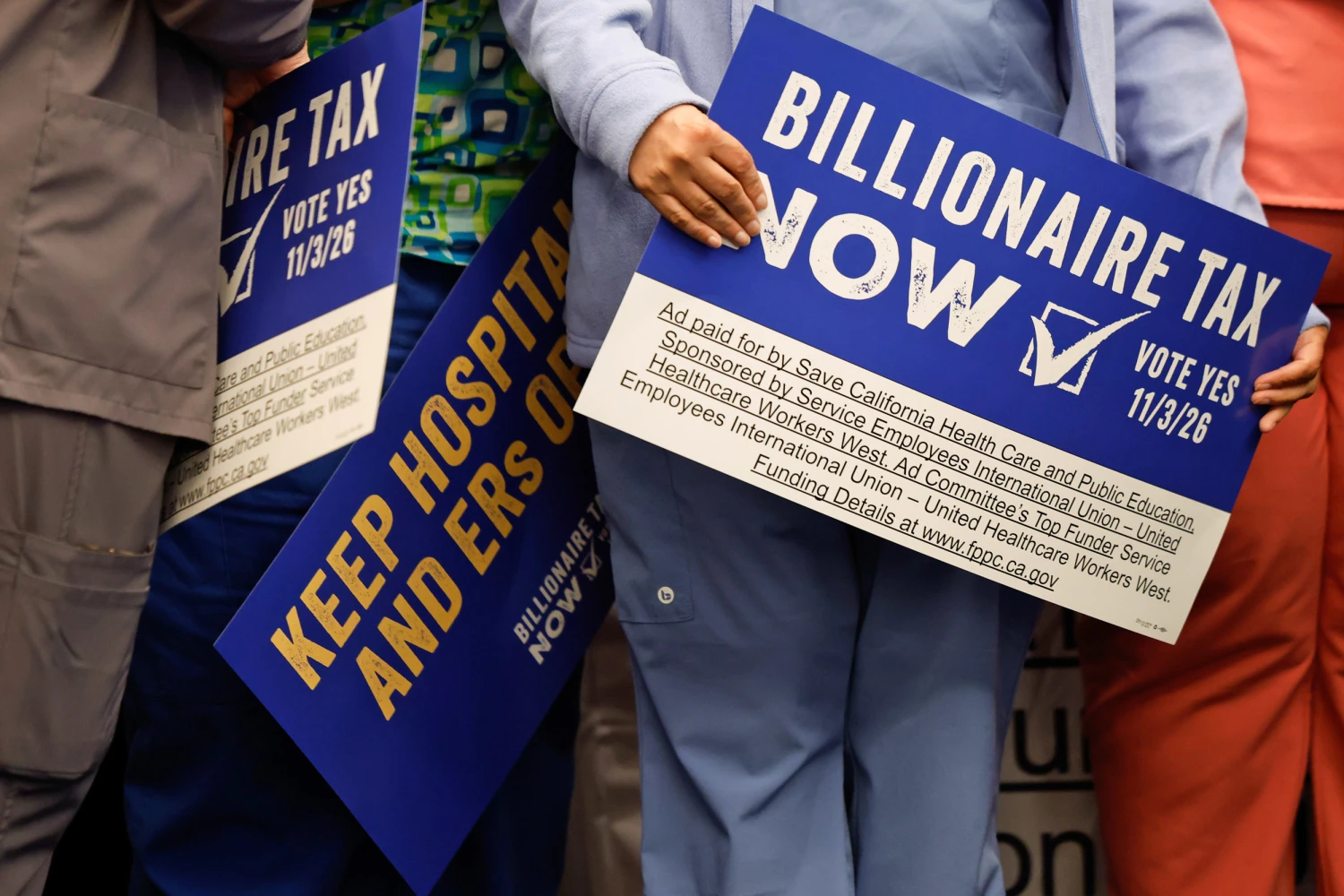 Supporters hold signs advocating for the "Billionaire Tax" in Los Angeles on April 27, 2026.
