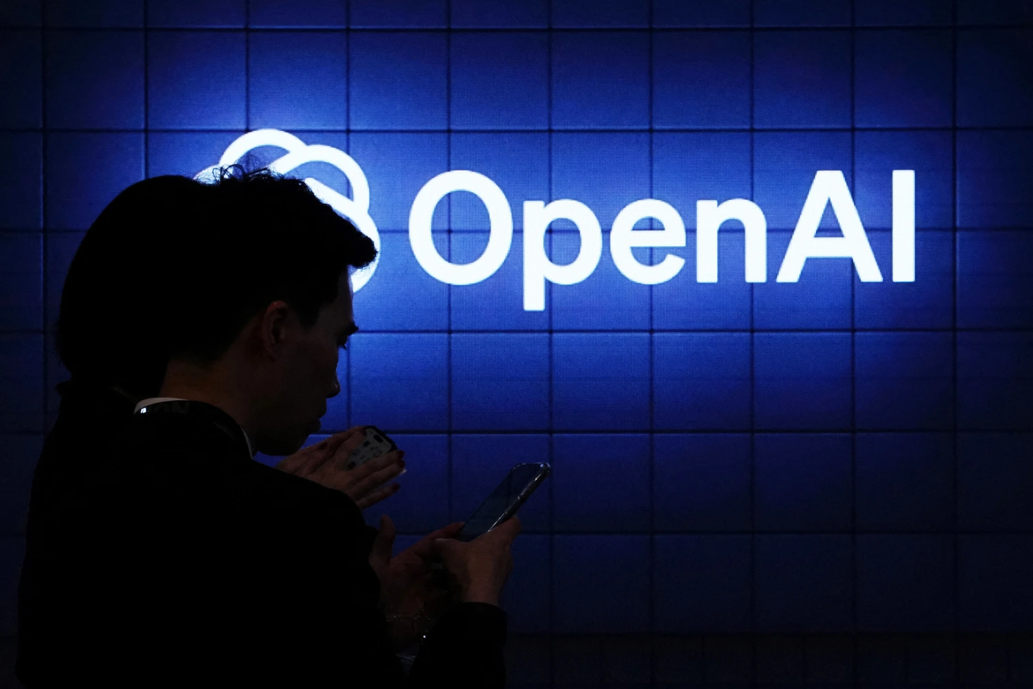 Visitor look at their phone next to an Open AI's logo during the Mobile World Congress (MWC), the telecom industry's biggest annual gathering, in Barcelona on February 26, 2024.