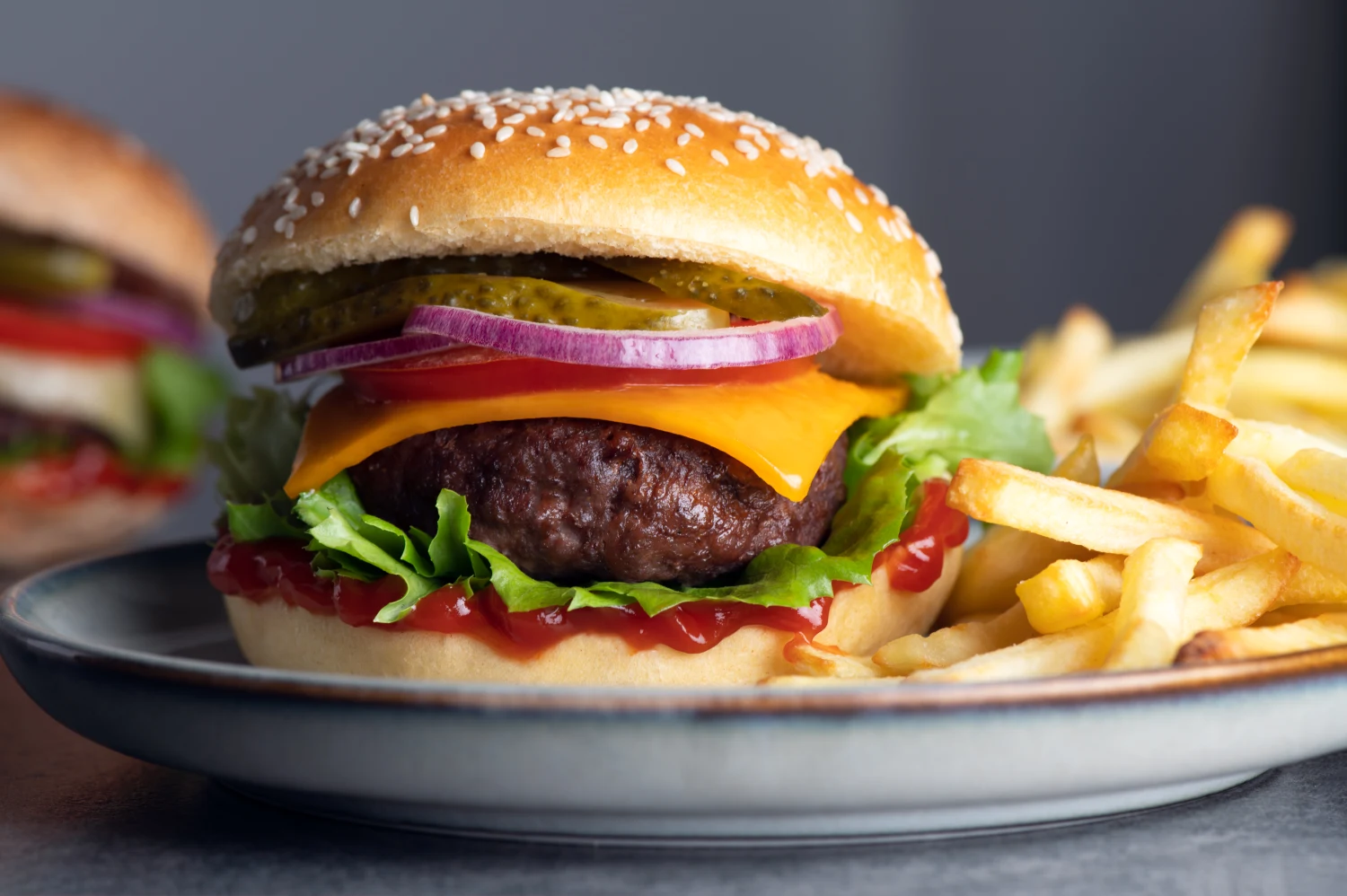 Homemade tasty freshly made burger with chips or french fries. Made from beef meat, cheese, salat leaves, tomatoes, onion, pickled cucumber and sauce