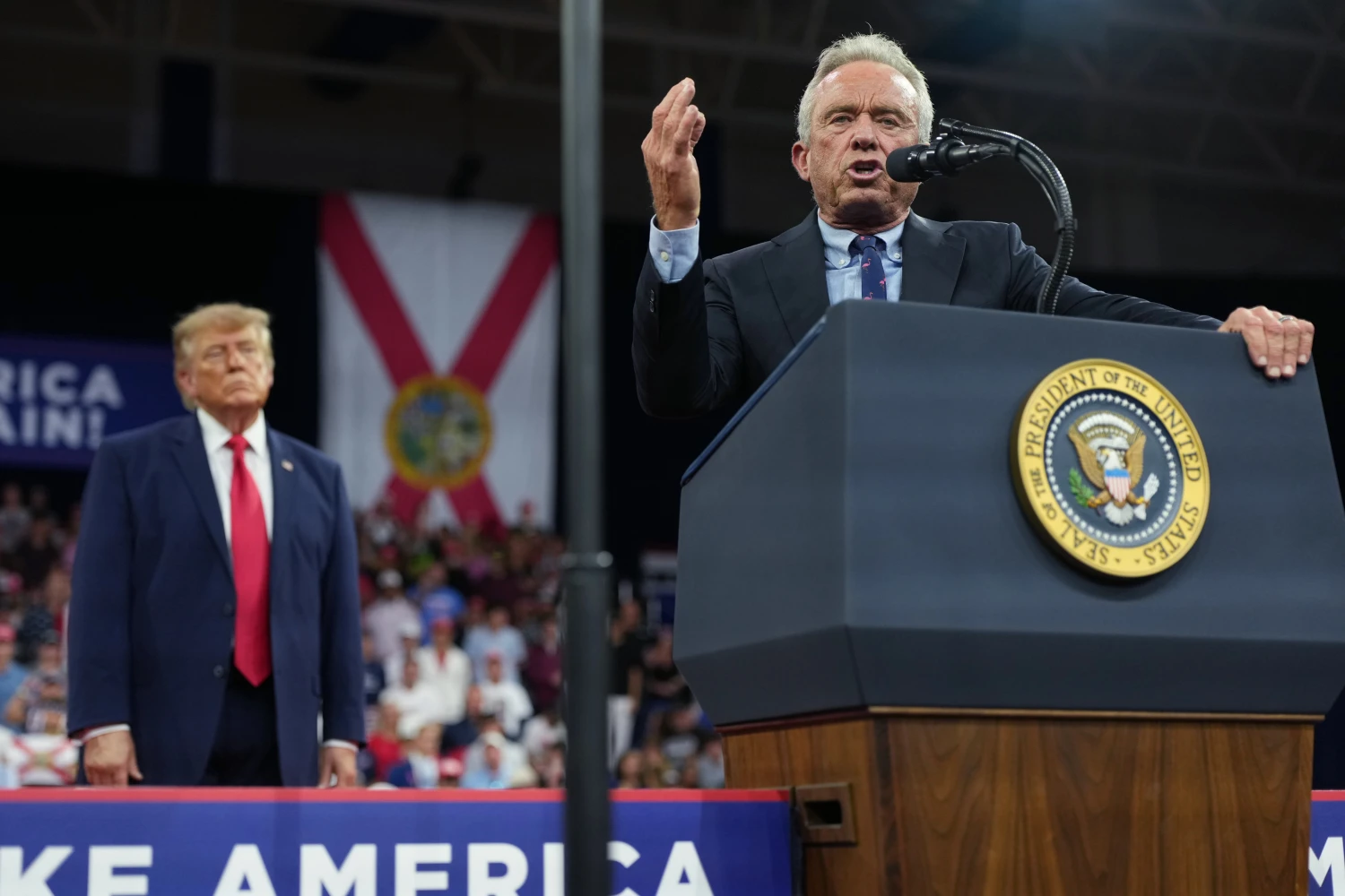 President Donald Trump listens as Health and Human Services Secretary Robert F. Kennedy Jr. speaks at a campaign rally at Alico Arena on the campus of Florida Gulf Coast University, Friday, Oct. 23, 2026, in Fort Myers, Fla. (AP Photo/Mark Schiefelbein)