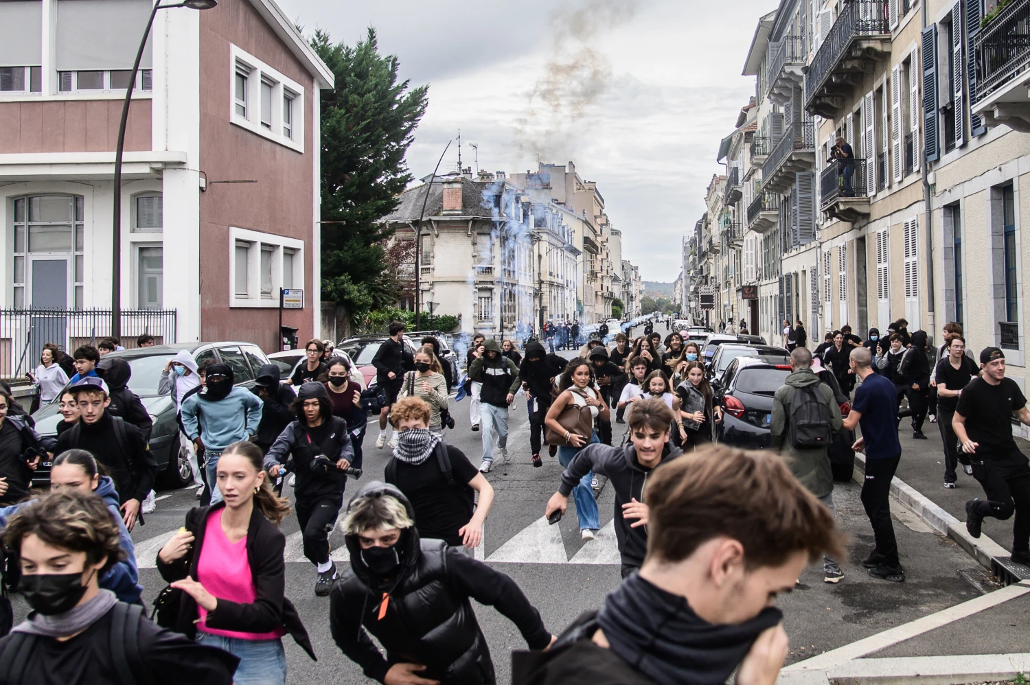 A group of young people runs down a city street through lingering smoke during the high school protest in Pau, Pyrenees-Atlantiques, Nouvelle-Aquitaine, France, on Oct 2.