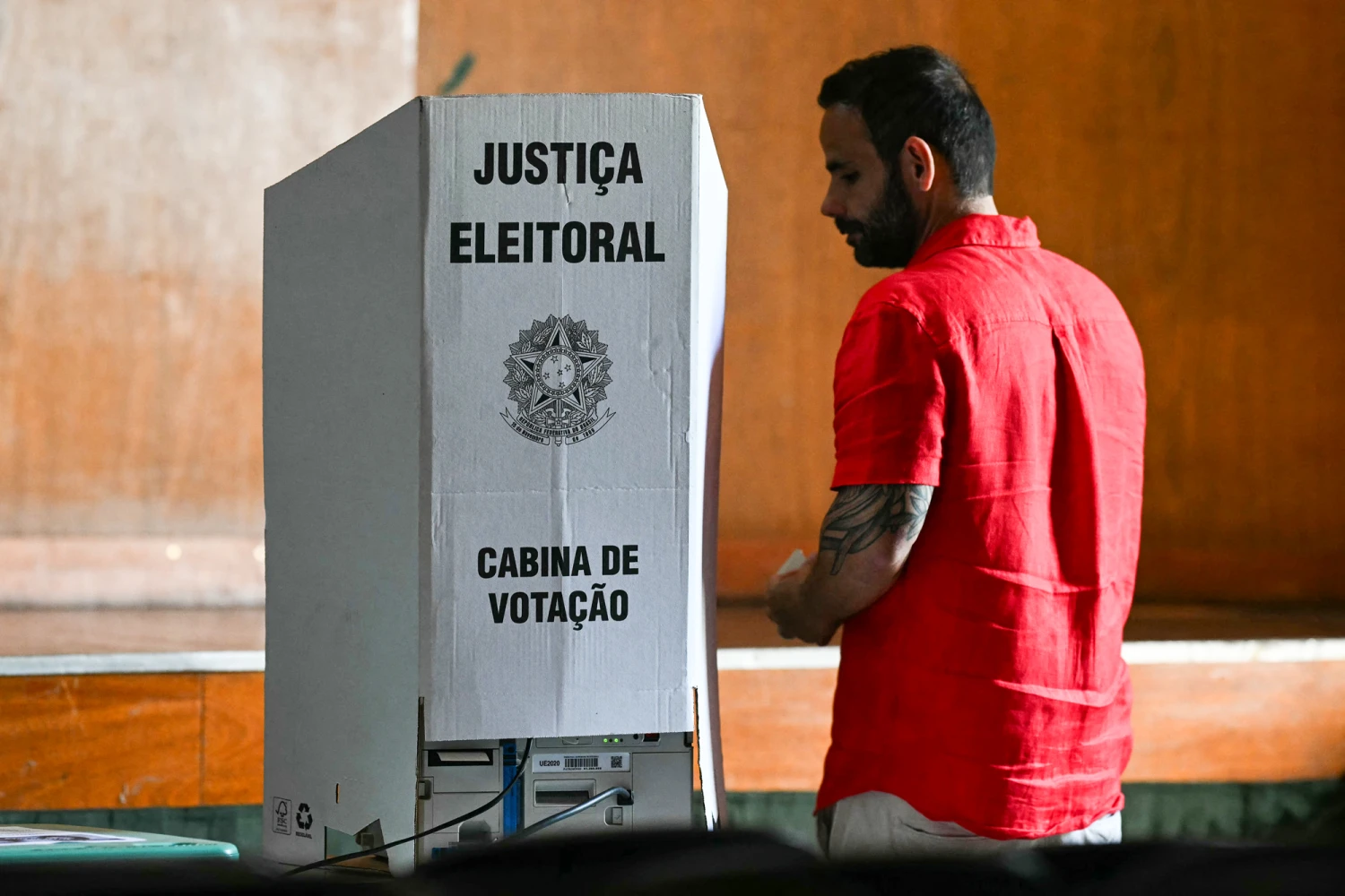 A voter stands beside a voting booth during the presidential election at a polling station in Rio de Janeiro, Brazil, on Oct. 4, 2026. Brazilians head to the polls in a highly polarized presidential election between incumbent leftist President Luiz Inacio Lula da Silva -seeking a fourth presidential mandate- and right-wing senator Flavio Bolsonaro, who emerged as the leading figure of the conservative movement following the conviction and imprisonment of his father, former president Jair Bolsonaro.