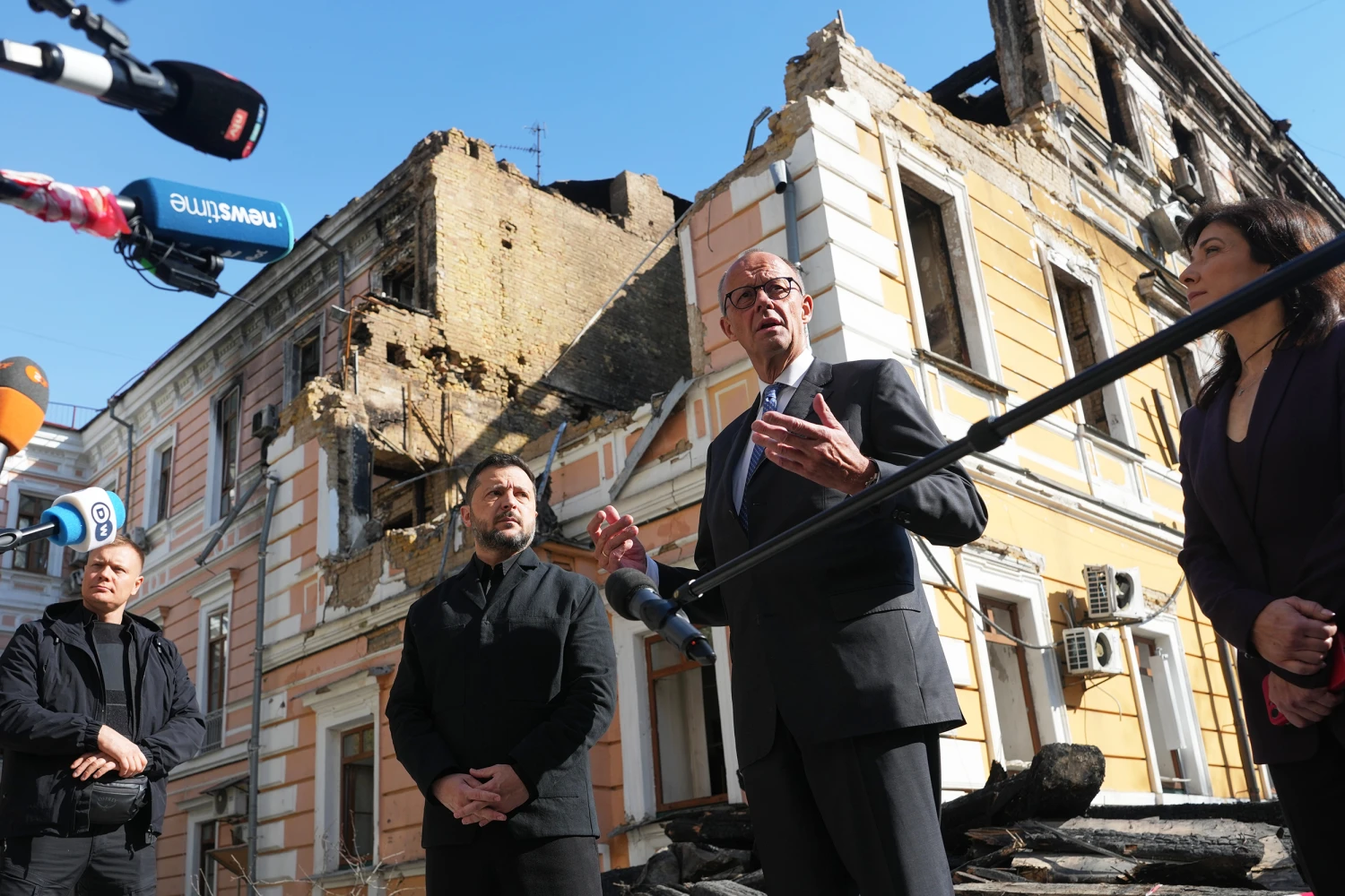 Ukraine's President Volodymyr Zelenskyy, centre, and German Chancellor Friedrich Merz speak to media with National Academy of science building damaged after a Russian drone strike, on the background, Kyiv, Ukraine, Sunday, Oct. 4, 2026.