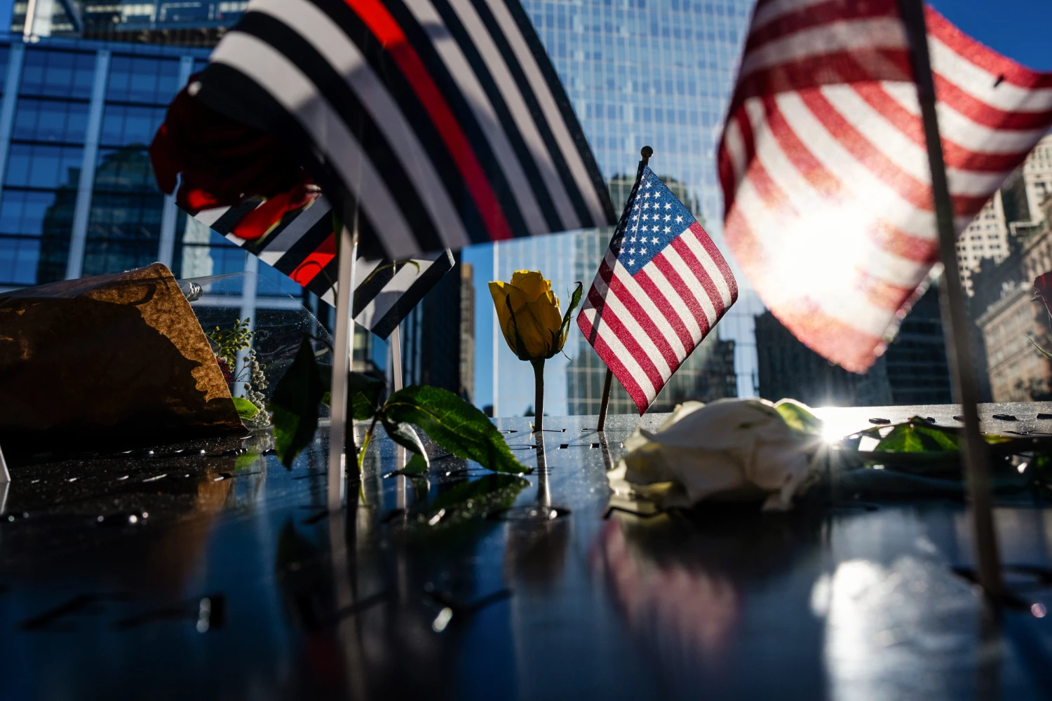 Flags and roses are placed on the edge of the 9/11 Memorial Pools on the 25th anniversary of the September 11 World Trade Center attacks Sept. 11, 2026, in New York.