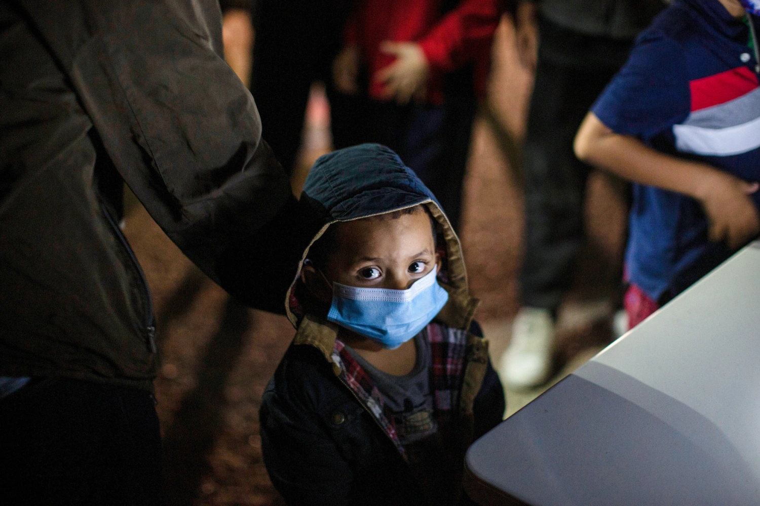 An unaccompanied minor looks up as he waits to answer questions from a U.S. Border Patrol agent at an intake site after he was smuggled on an inflatable raft across the Rio Grande River, on March 24, 2021, in Roma, Texas.
