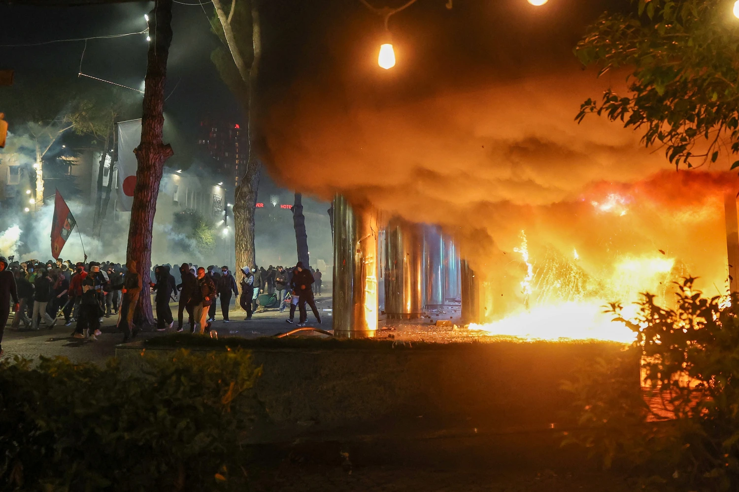 Smoke billows from a fire near a group of protesters during clashes with riot police in central Tirana on October 14, 2026, as violence erupted for a second consecutive day during demonstrations demanding the resignation of Albanian Prime Minister Edi Rama and better education.
