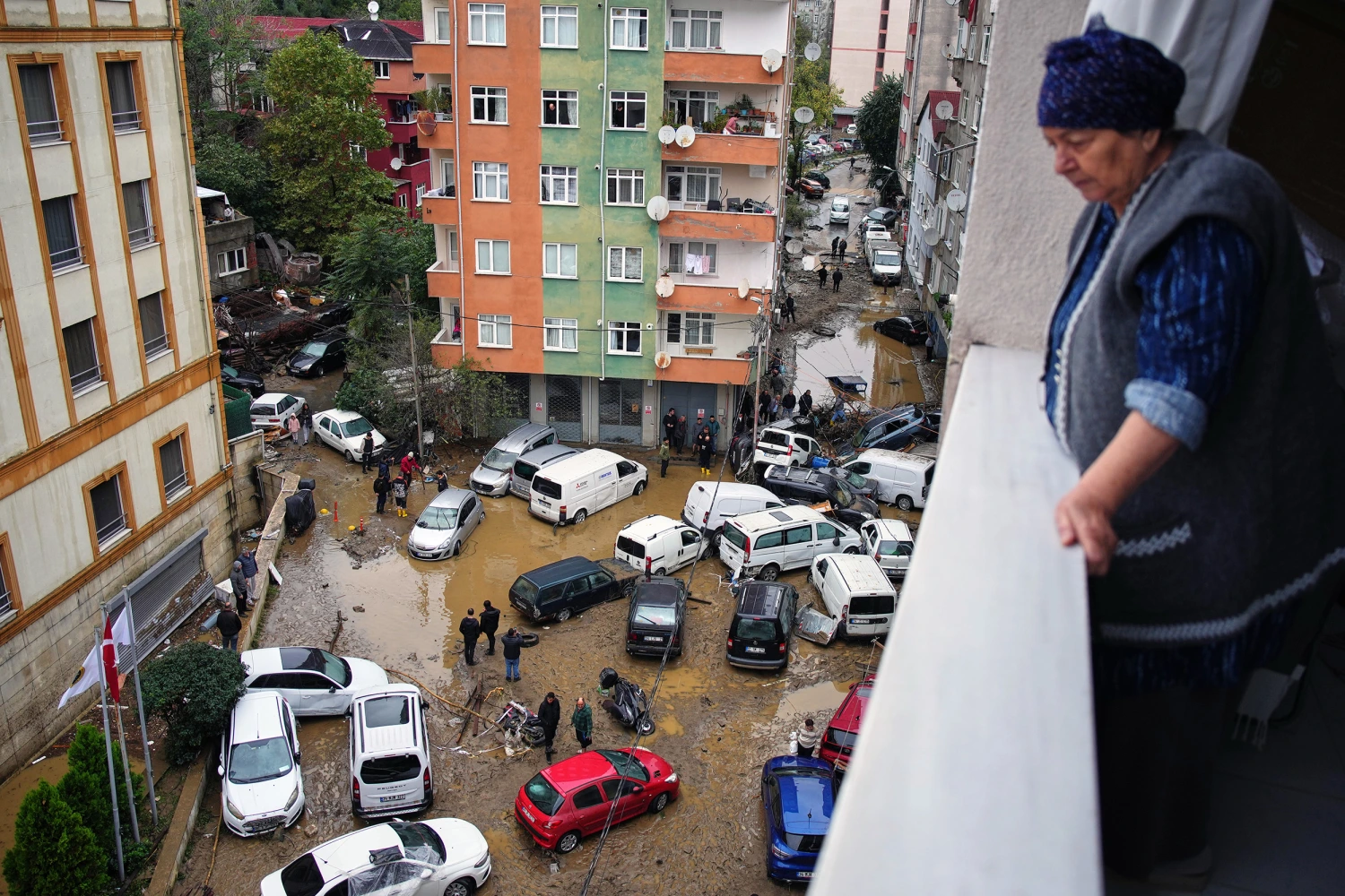 Local residents walk among toppled vehicles and scattered debris in the aftermath of floods caused by heavy rains, in Istanbul, Turkey, Thursday, Oct. 15, 2026.