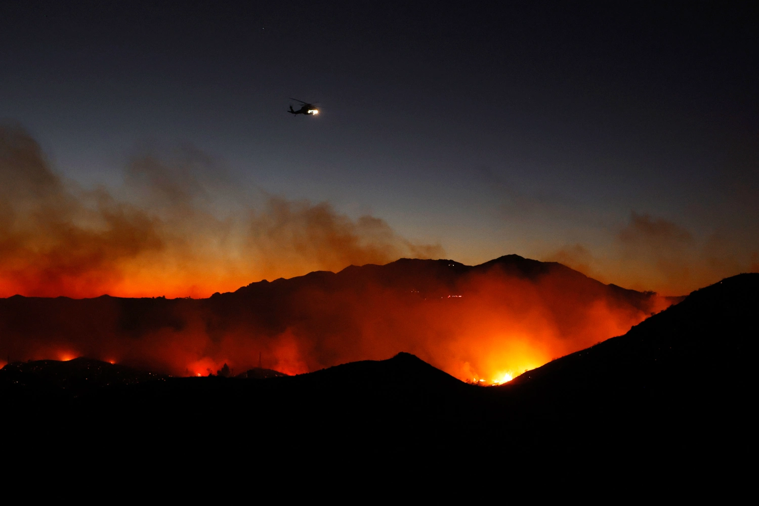 A firefighting helicopter over the Bryson Fire on October 15, 2026 in Malibu, California. Firefighters are battling the Bryson Fire that has burned over 100 acres and is zero percent contained.