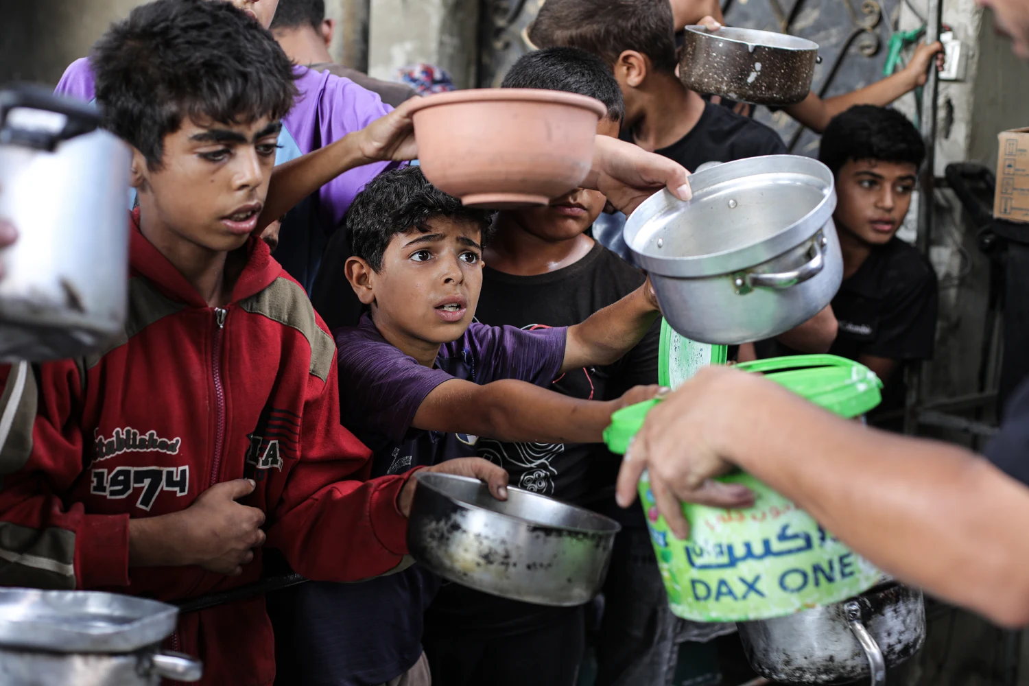 Palestinians, including many children holding cooking pots and plastic containers, gather in large crowds to receive hot meals during a food aid distribution at the Nuseirat refugee camp in the central Gaza Strip on October 08, 2026.