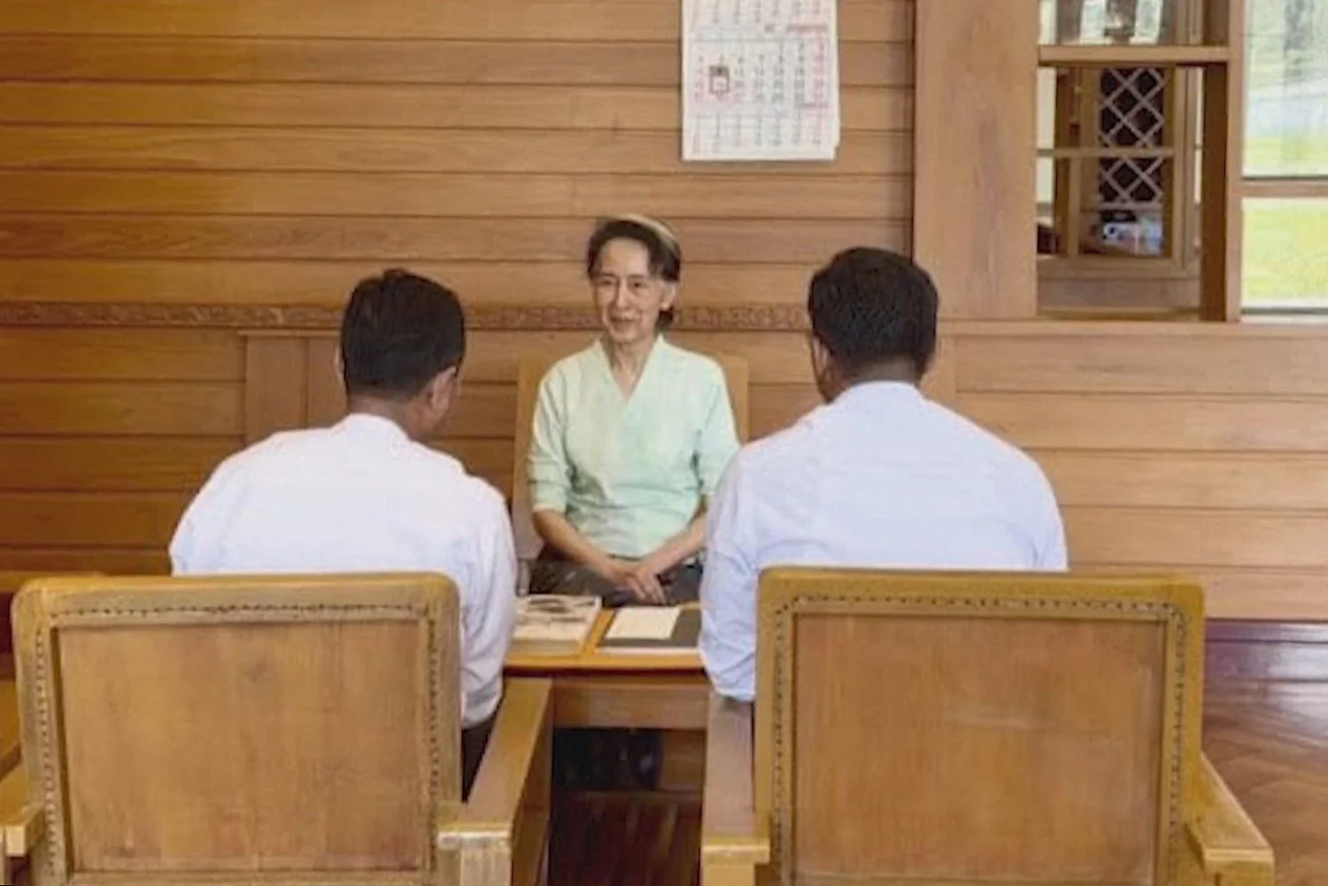 Aung San Suu Kyi talks with officials from Home Affairs Ministry as she receives two books and a sealed letter sent by Britain's King Charles III.