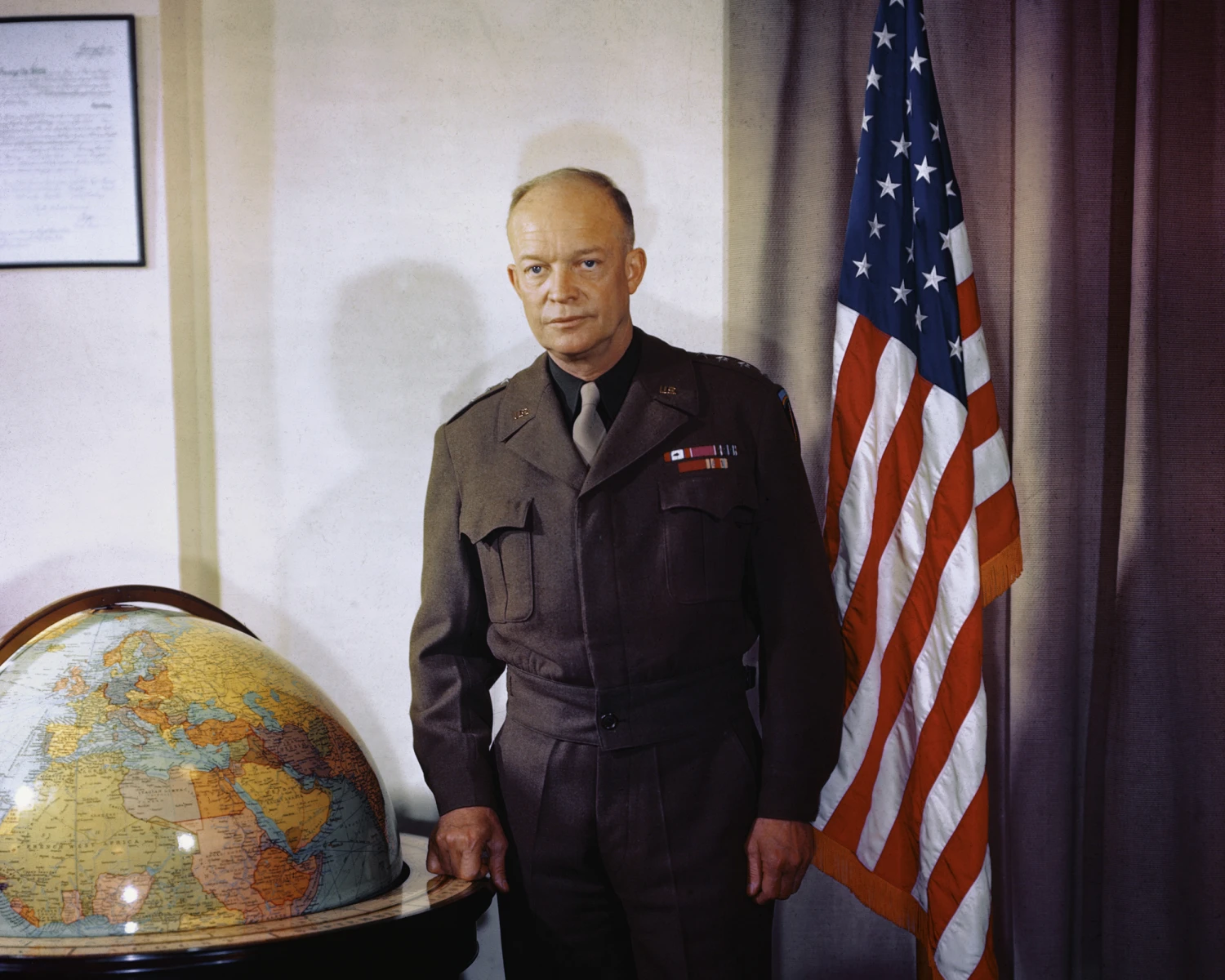Dwight D. Eisenhower is shown in a portrait, standing near a globe and a flag.