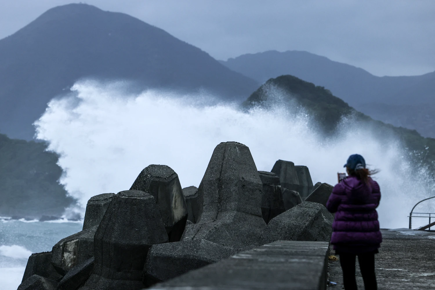 A woman takes pictures of waves as Typhoon Champi approaches Taiwan in Keelung on October 22, 2026.