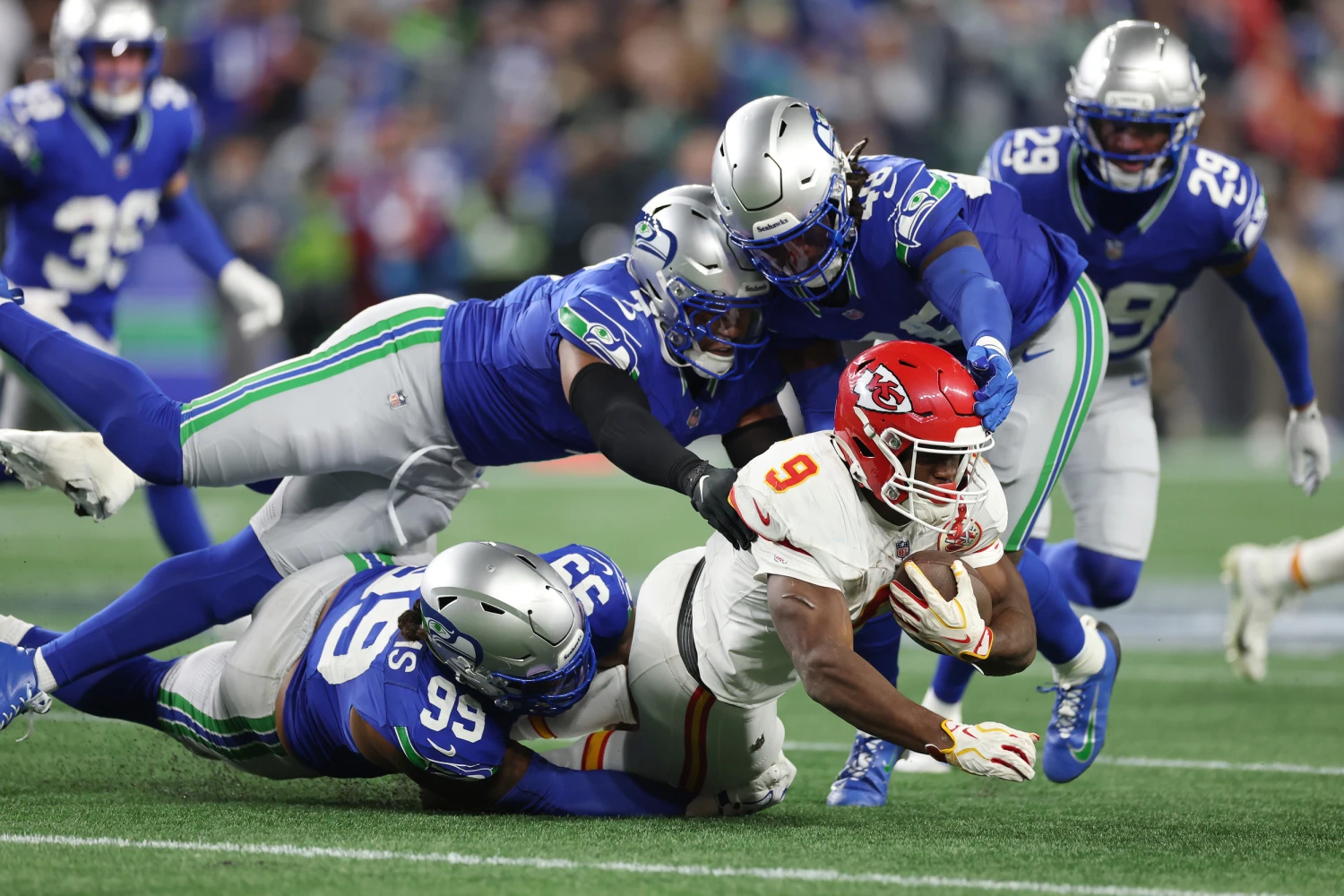 Chiefs running back Kenneth Walker III is tackled by Leonard Williams, Uchenna Nwosu and Tyrice Knight of the Seahawks.