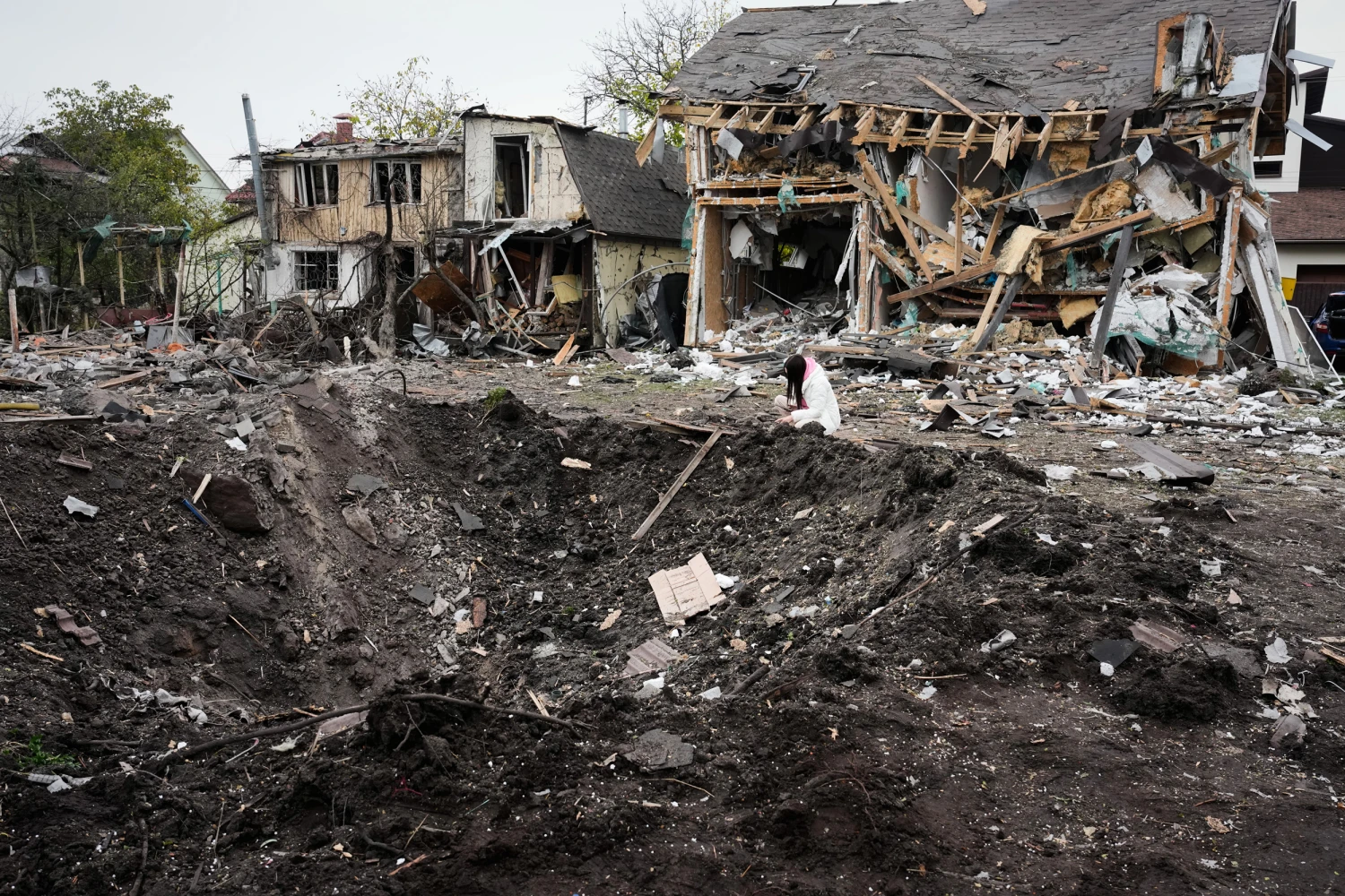 A woman looks at a crater after a Russian missile strike in Kyiv, Ukraine, Thursday, Oct. 22, 2026.