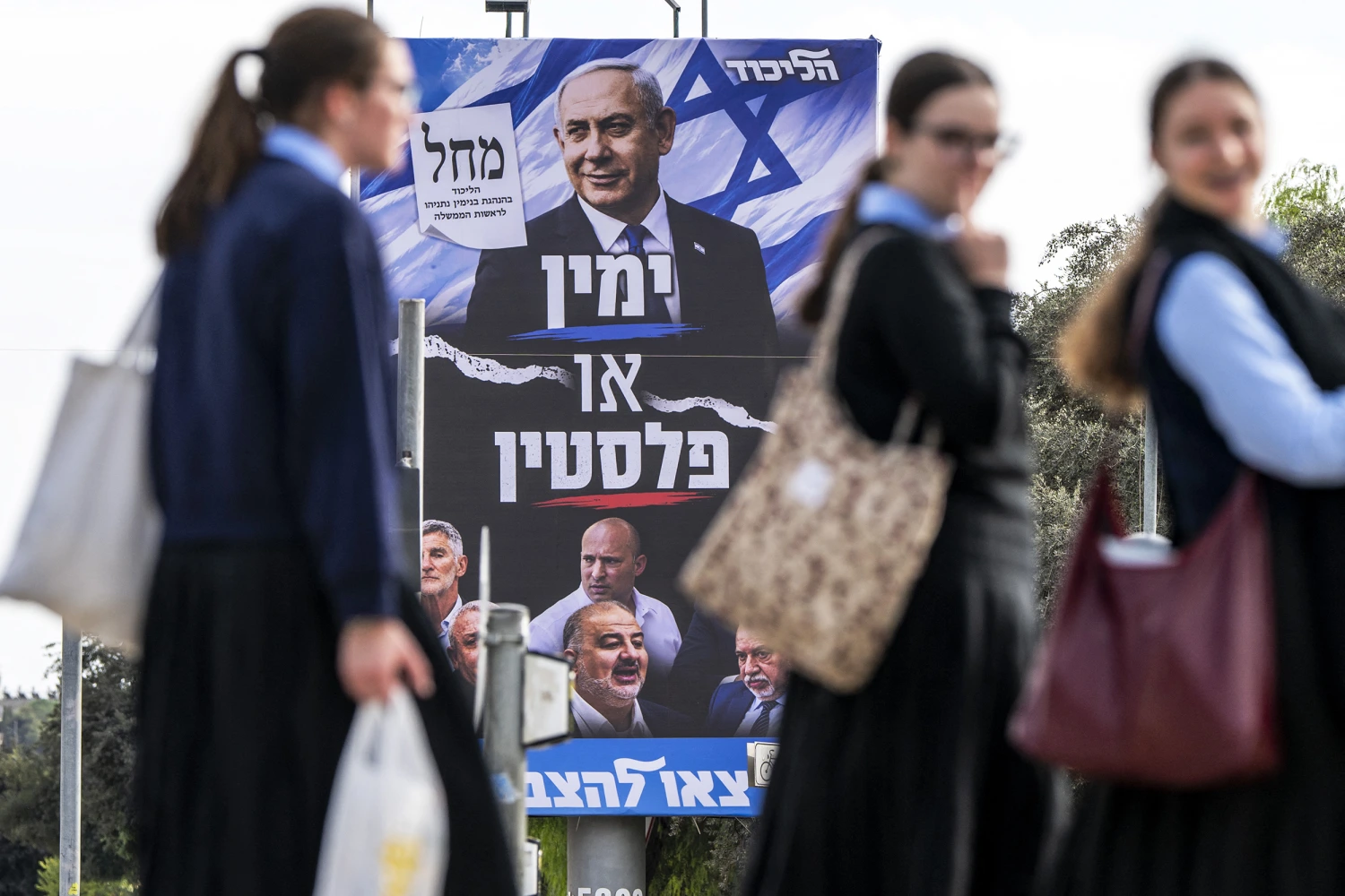 Girls walk past an electoral campaign billboard for Israeli Prime Minister Benjamin Netanyahu's Likud party in Jerusalem on Tuesday.