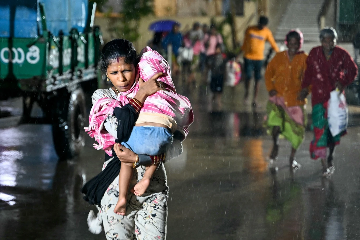 TOPSHOT - A woman with a child arrives at a relief shelter during rainfall in Andhra Pradesh's Kakinada on October 27, 2026 ahead of cyclone Arnab's expected landfall. (Photo by Noah SEELAM / AFP via Getty Images)