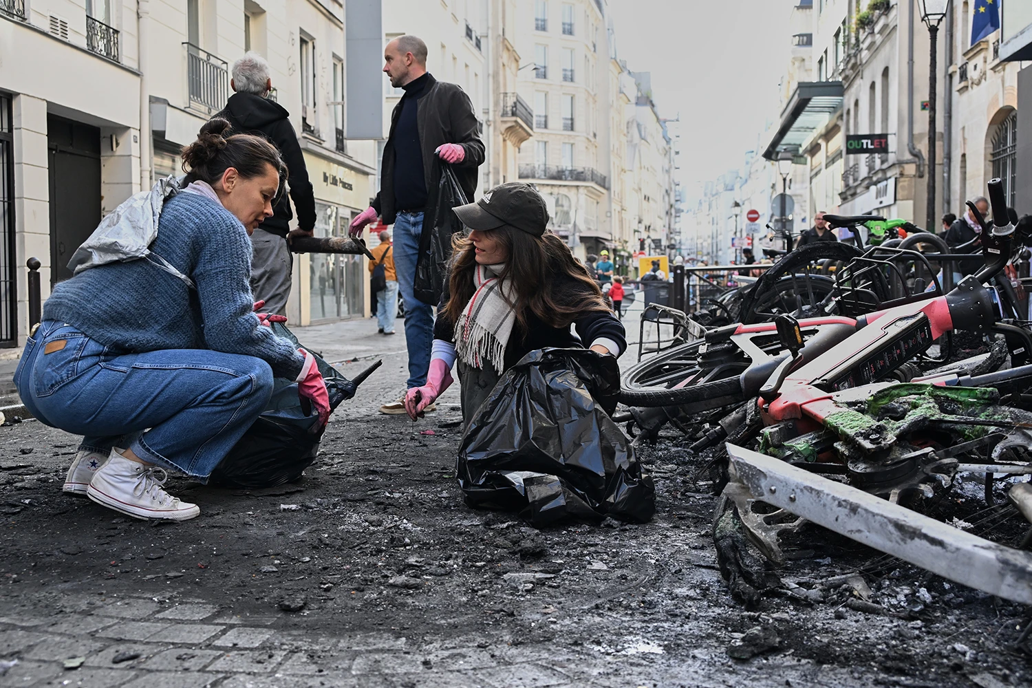 People clean up debris following violent protests in Paris on Oct. 18, 2026.