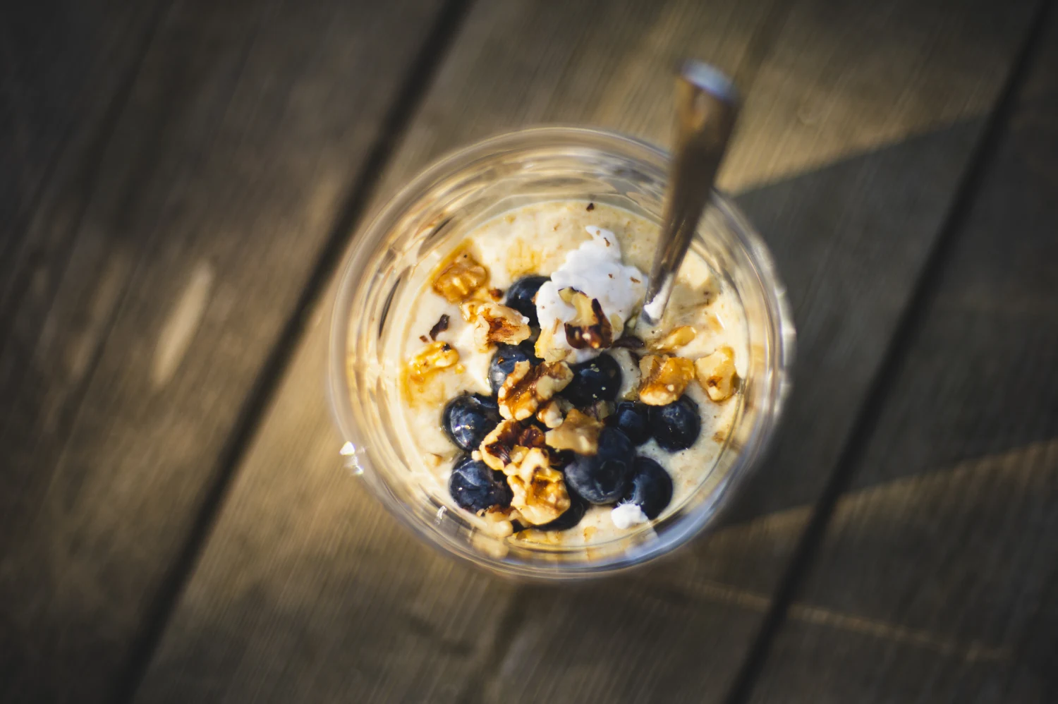 Vegan Healthy breakfast pot of chia seeds granola blueberries walnuts and coconut yogurt in glass bowl in sunlight
