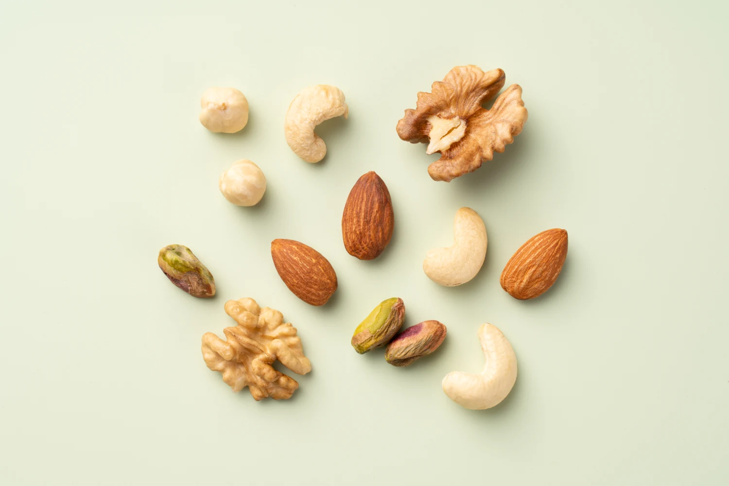 Mixed Nuts Assortment Include Hazelnut, Pistachio, Walnut, Almond and Cashew Nuts Arranged on Light Green Colored Background Directly Above View.