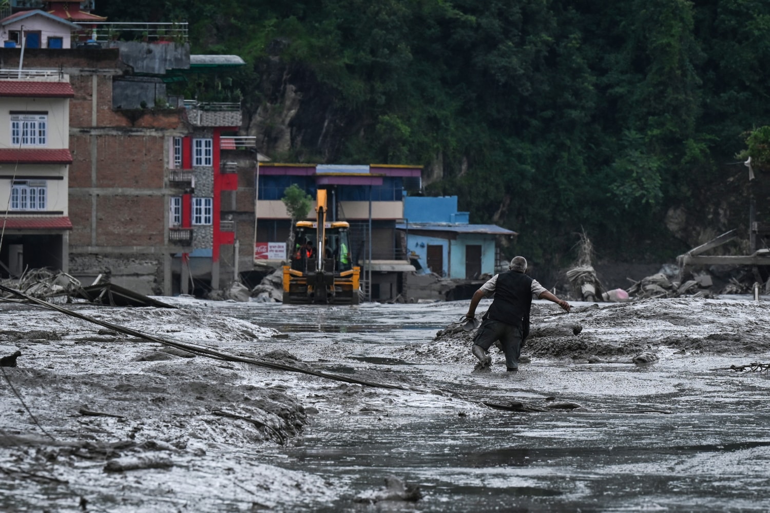 A resident walks along a street covered in mud following flash floods and a landslide disaster in Devighat, in Nepal's Nuwakot district on August 26, 2026.