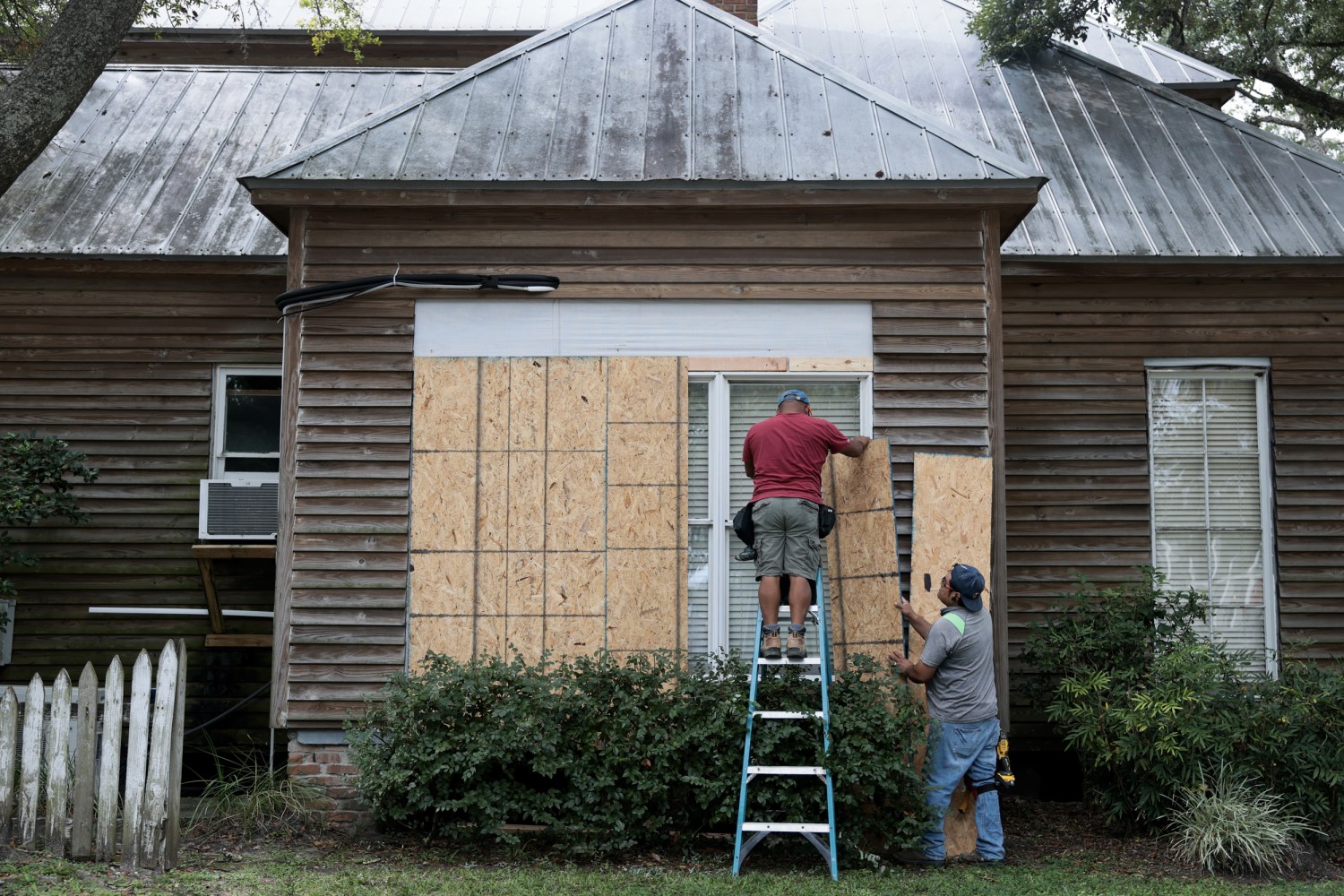 Aaron Chi and Wilner Garcia place plywood over the windows of a home as they prepare for the possible arrival of Hurricane Isaias on October 08, 2026 in Pensacola, Flo.