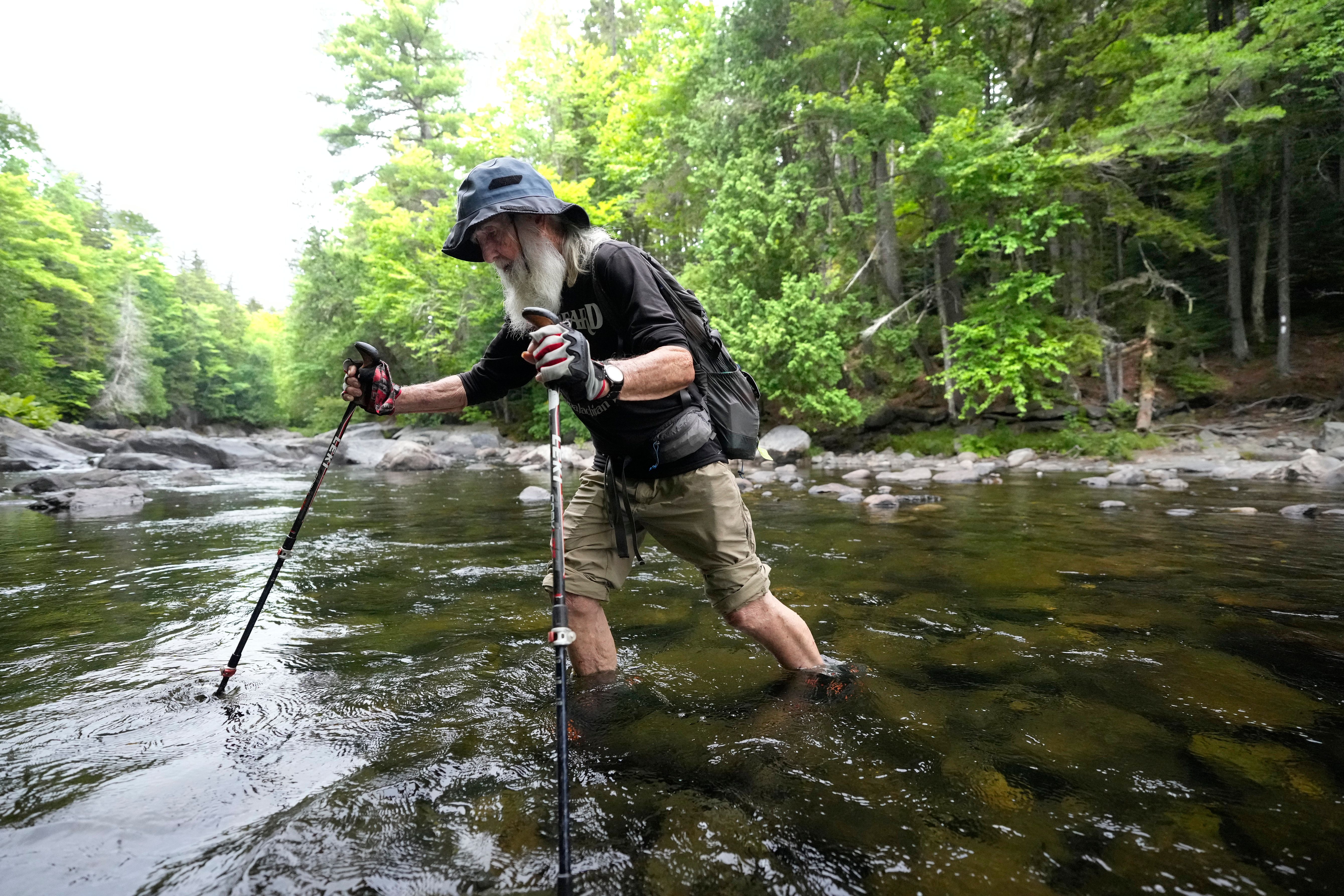 Appalachian Trail hiker Dale Sanders wades across Big Wilson Stream on the 100-Mile Wilderness north of Monson, Maine, Wednesday, July 29, 2026.