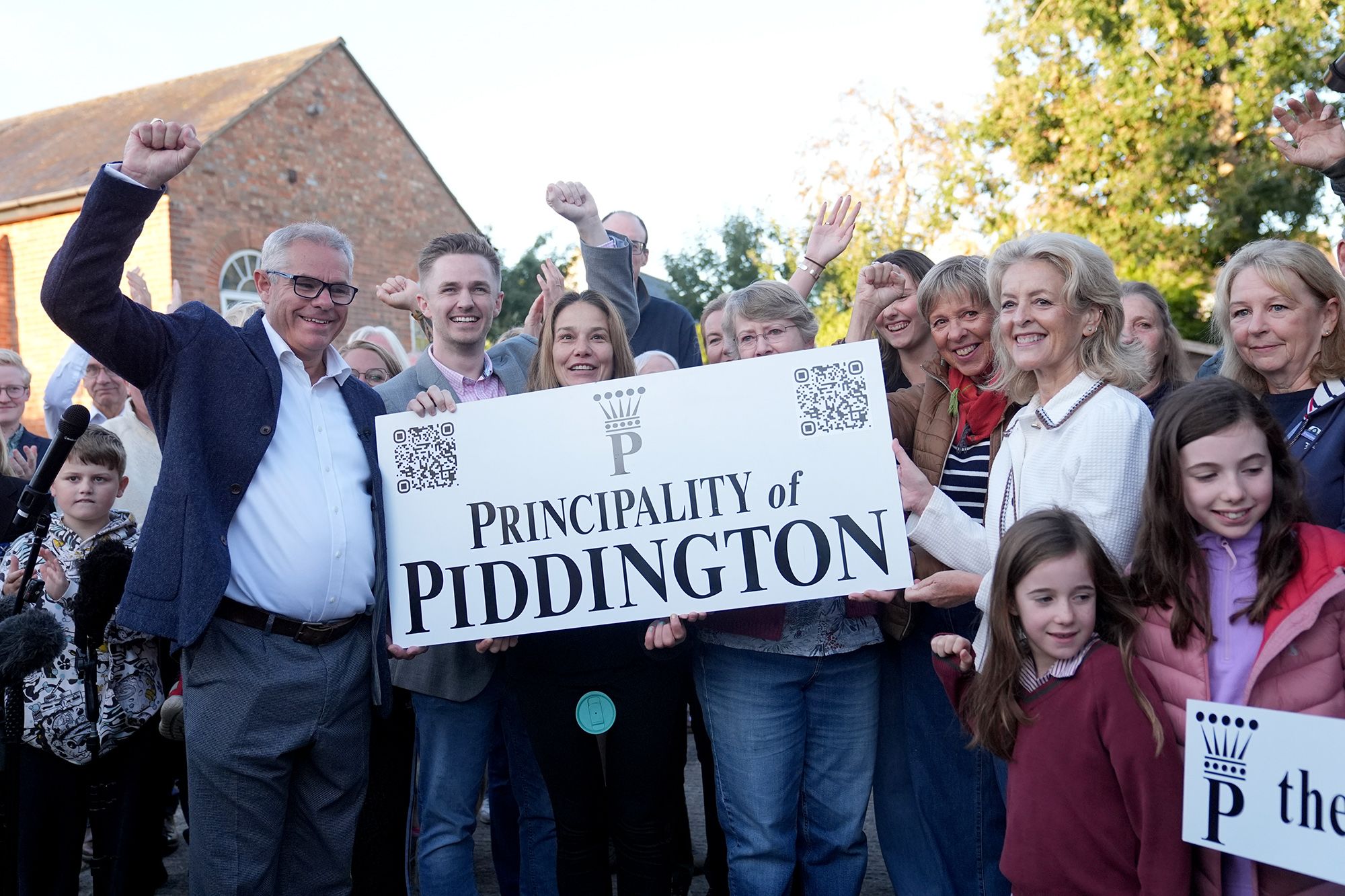 Locals hold a sign reading "Principality of Piddington" following a symbolic vote to secede from the UK.