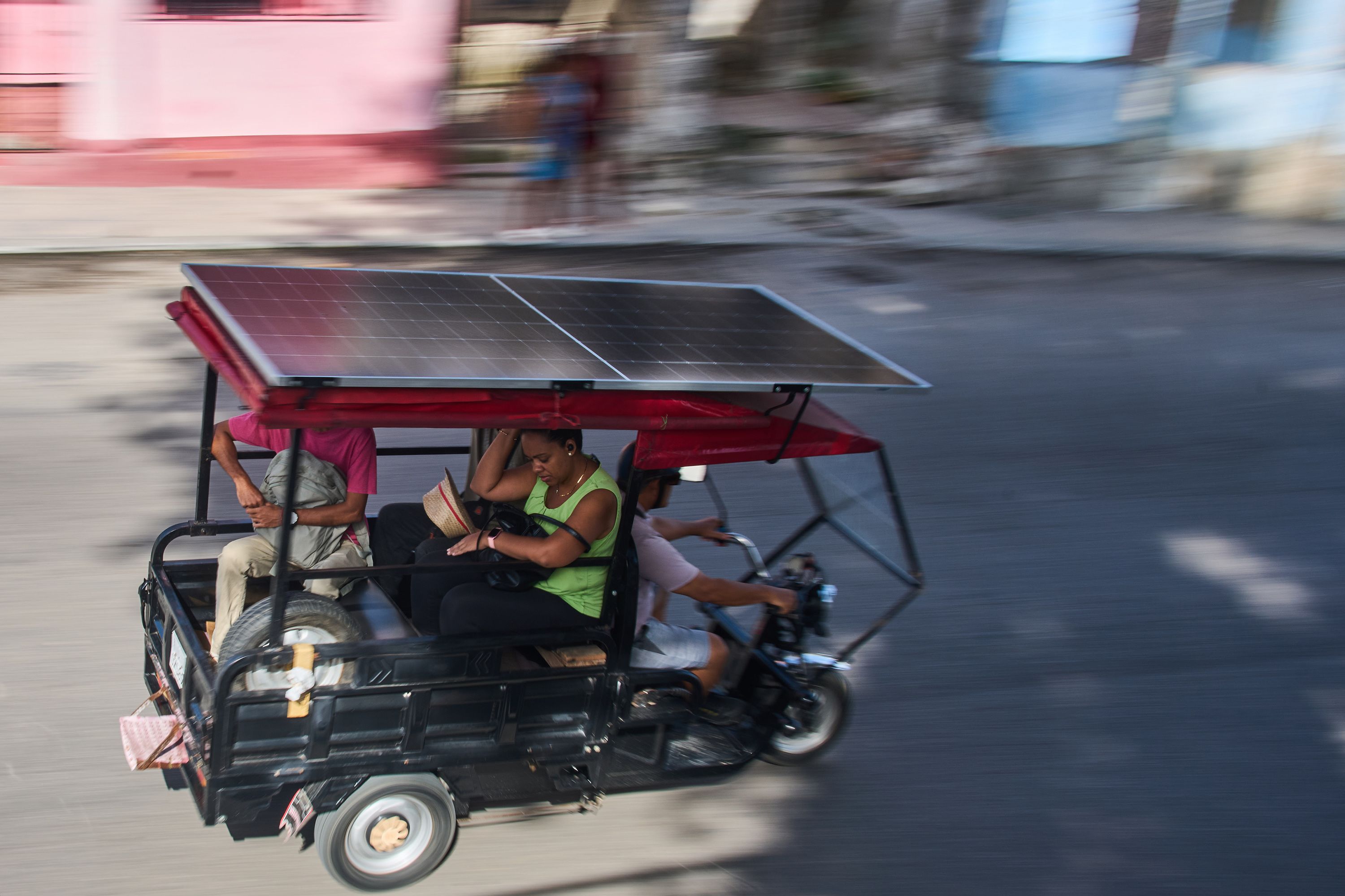 People ride in an electric tricycle equipped with a solar panel in Havana, Cuba, on July 10.