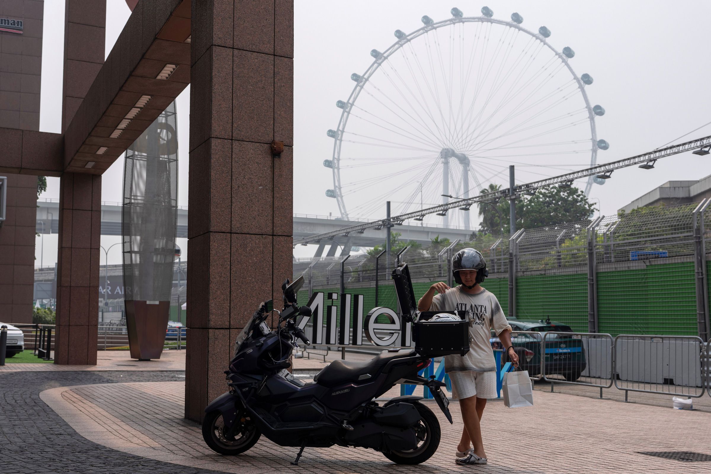 A man places bags in his motorcycle during a hazy day near the venue for the Singapore Formula One Grand Prix weekend at the Marina Bay Street Circuit in Singapore, Friday, Oct. 9, 2026.