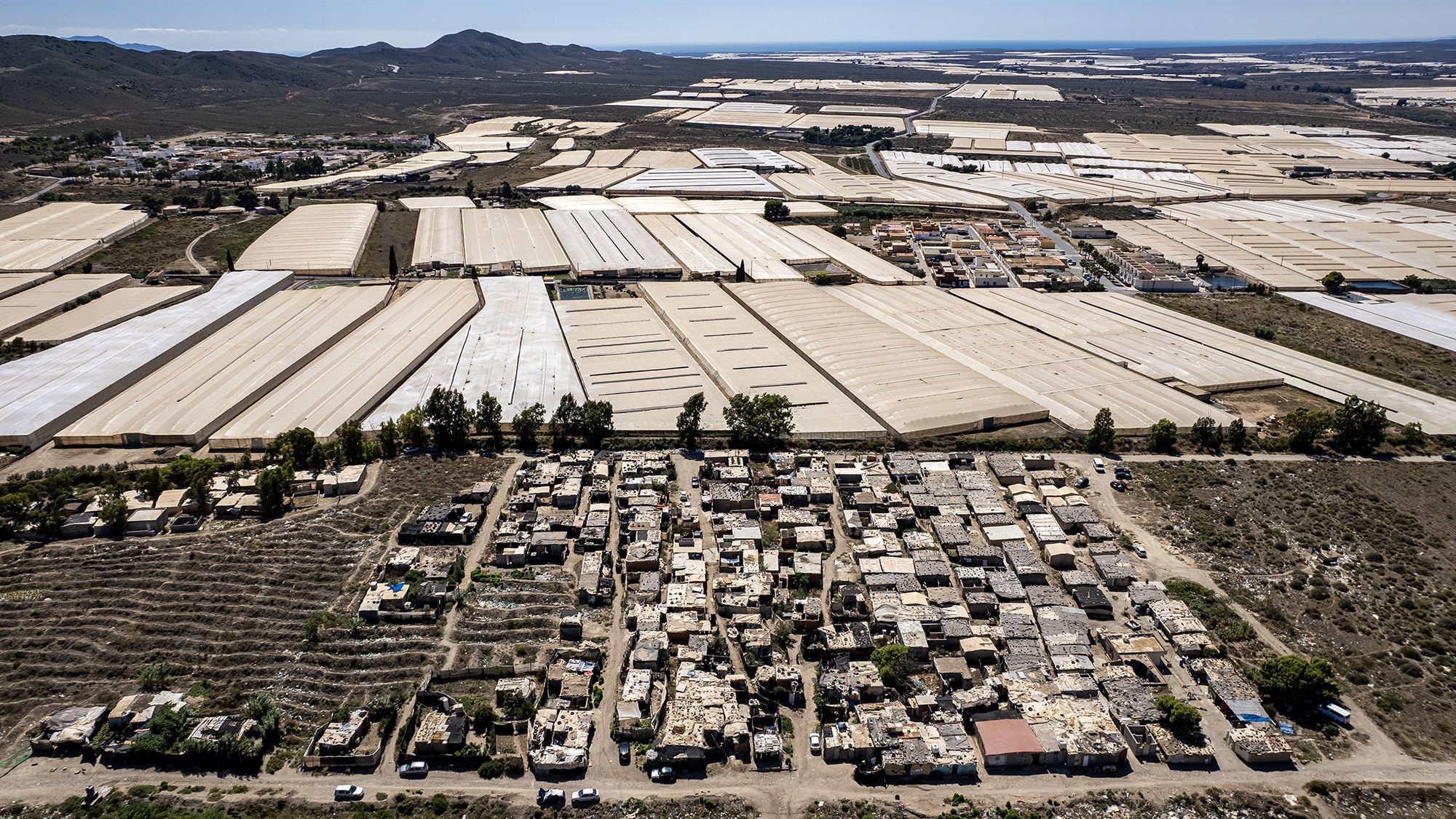 ALMERIA, SPAIN - SEPTEMBER 9: An aerial view of the camp for immigrant workers who work in greenhouse agriculture (invernaderos in Spanish) near the town of Nijar on September 9, 2023 in Almeria, Spain. The transparent plastic greenhouses intensify the heat and maintain humidity, allowing earlier harvests than in an open field. Almería's greenhouses cover more than 40,000 hectares (150 square miles) and now produce between 2.5 million and 3.5 million tons of fruit and vegetables per year, enough to make them a major source of off-season tomatoes, peppers, cucumbers, and melons for people all over Europe. (Photo by Octavio Passos/Getty Images)