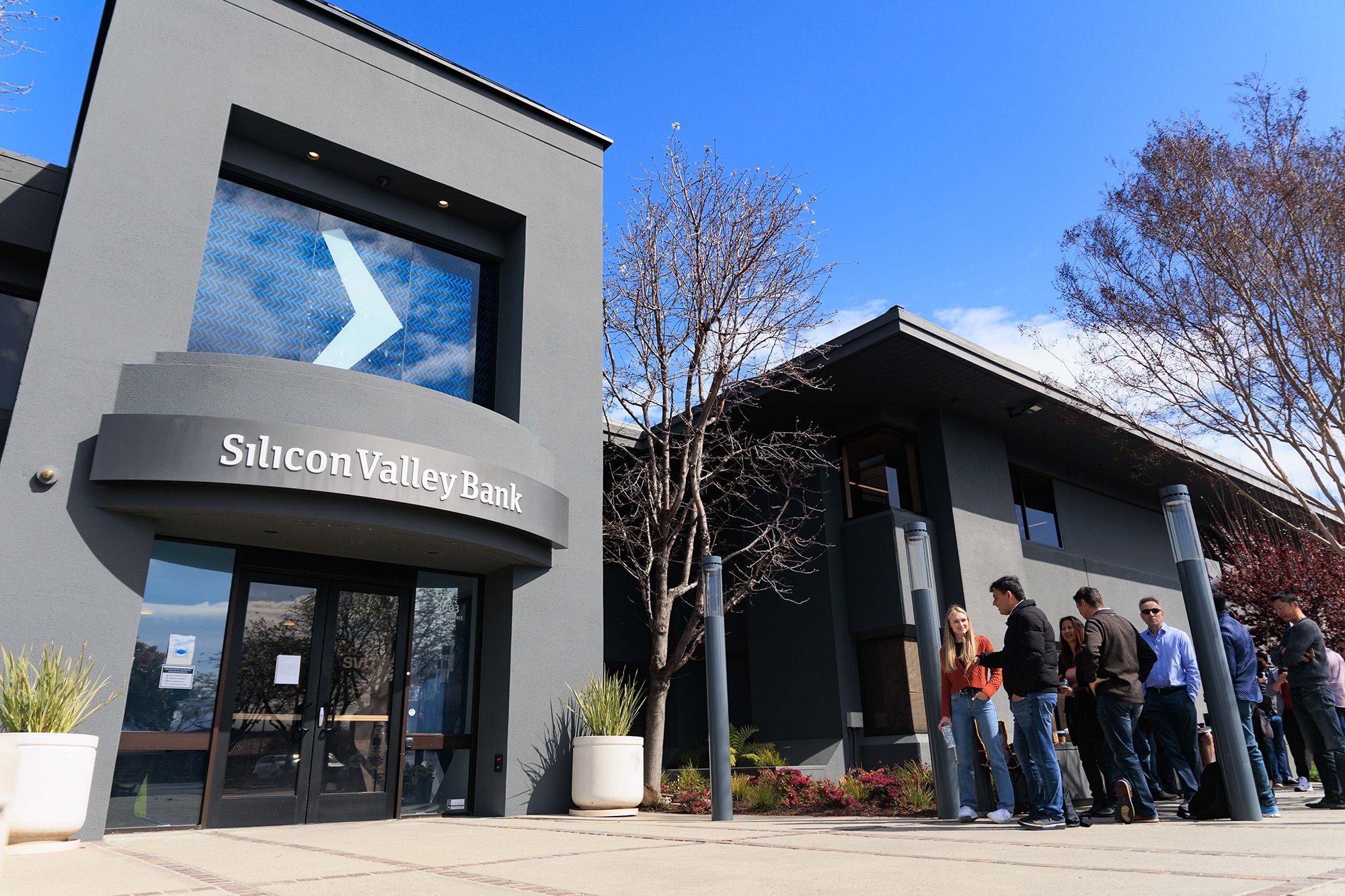 People wait outside the Silicon Valley Bank headquarters in Santa Clara, California, to withdraw funds after the federal government intervened upon the bank's collapse, on March 13, 2023.