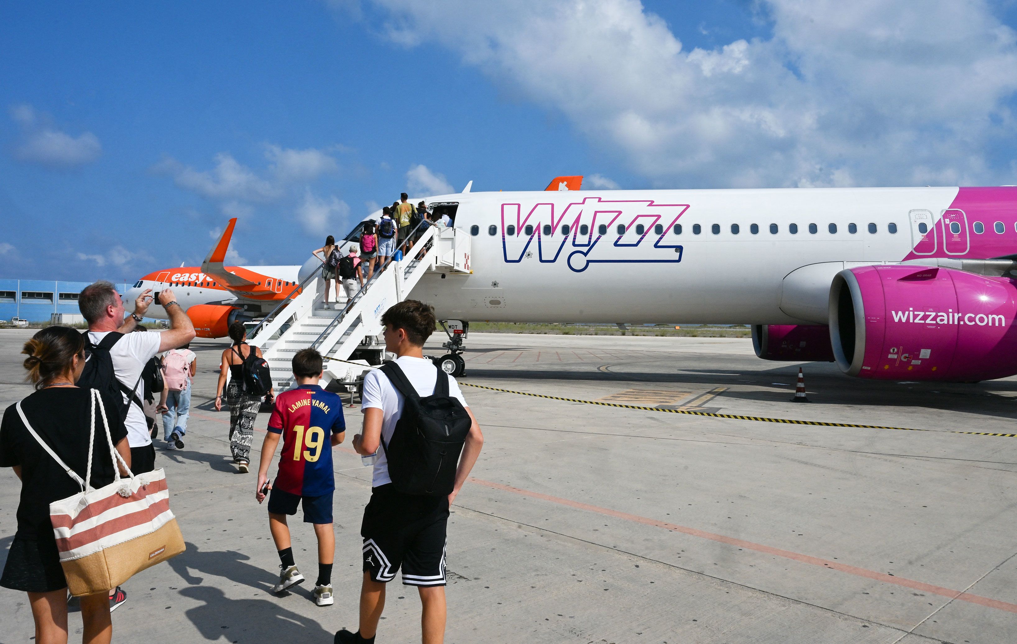Passengers embark aboard a Wizz air jet at the Lampedusa airport, on August 17, 2025.