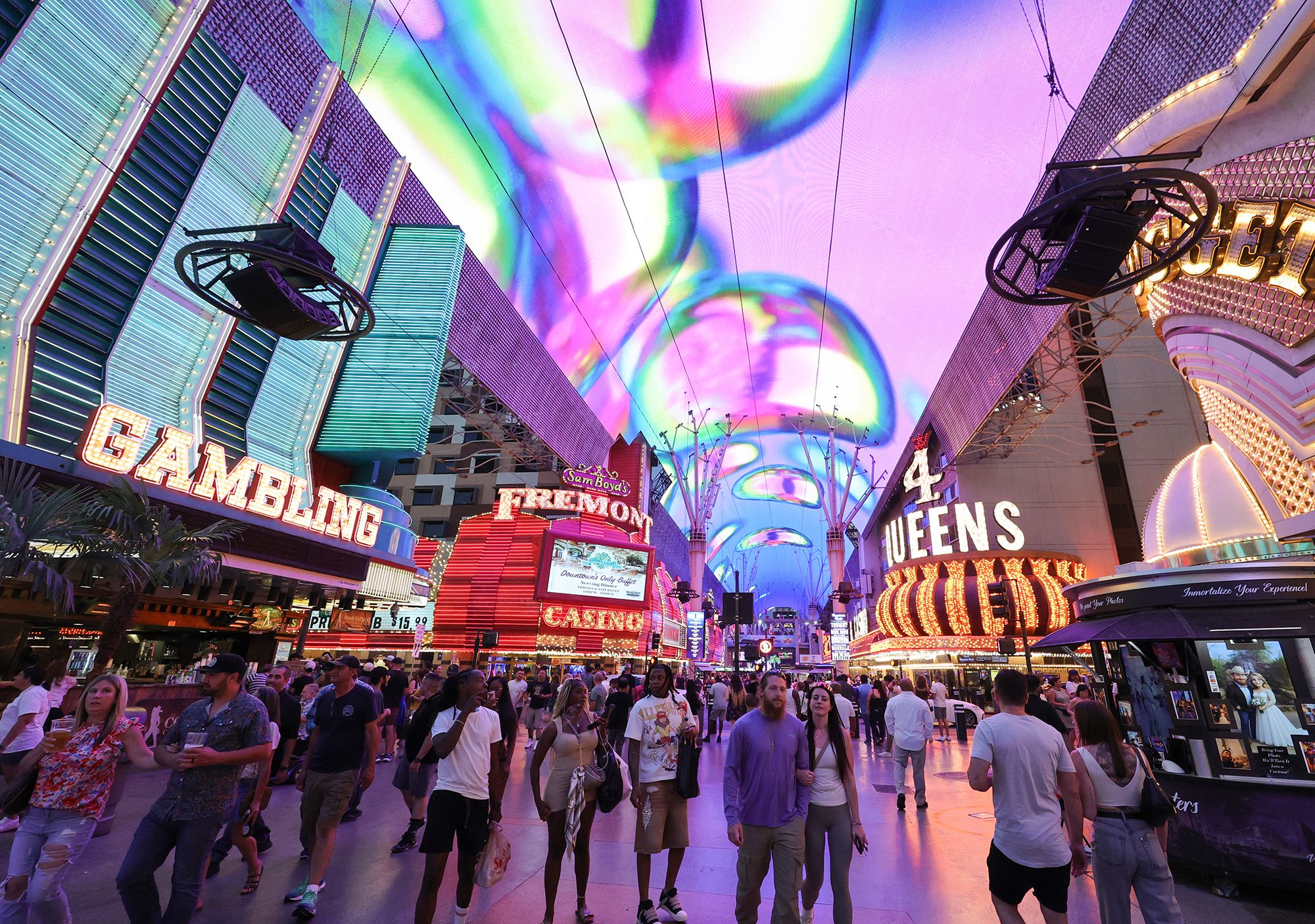 People walk under the Fremont Street Experience attraction's Viva Vision canopy screen on August 30, 2025, in downtown Las Vegas, Nevada..