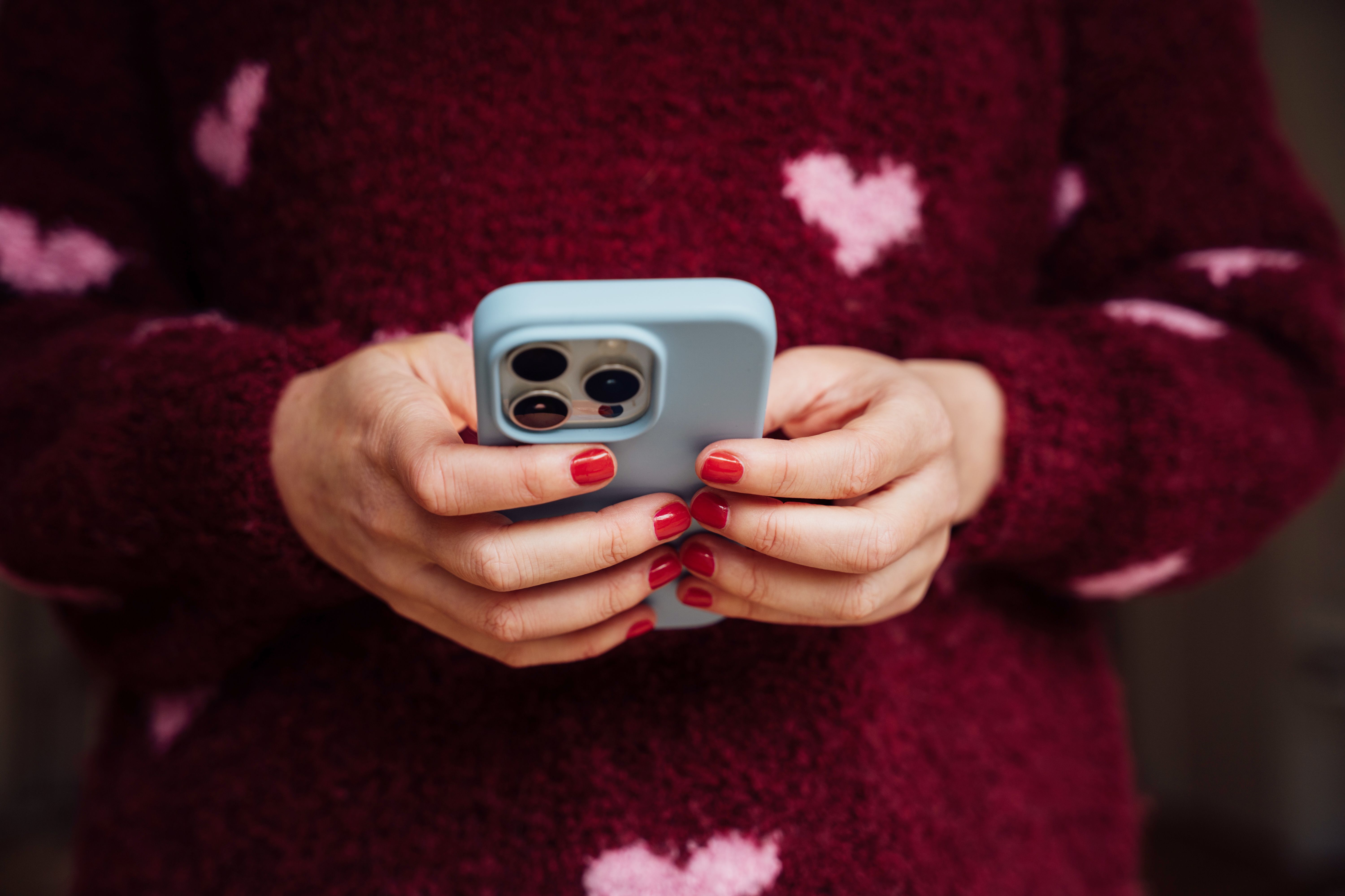 A woman types on a smartphone.
