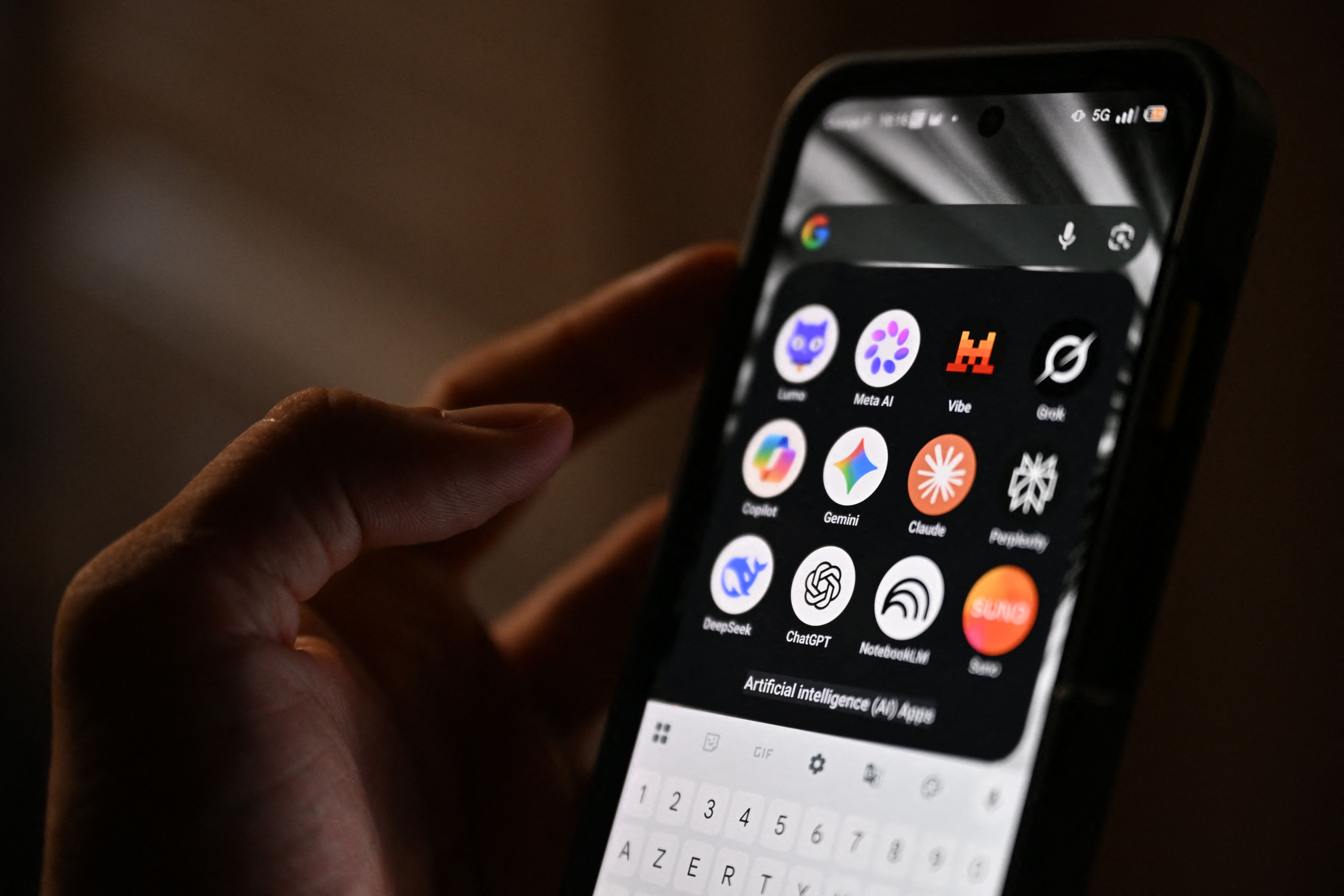 This photograph shows a handheld smartphone displaying the icons of some of the main artificial intelligence based apps, including LLMs, chatbots and generative AI, with logos (from L) of Proton AG's Lumo, Meta AI, Mistral Vibe (formerly Le Chat), xAI's Grok, Microsoft's Copilot, Google's Gemini, Anthropic's Claude, Perplexity, Deepseek, OpenAI's Chat GPT, Google's Notebook LLM and generative AI music app Suno, in Saint-Mande, east of Paris, on July 15, 2026.